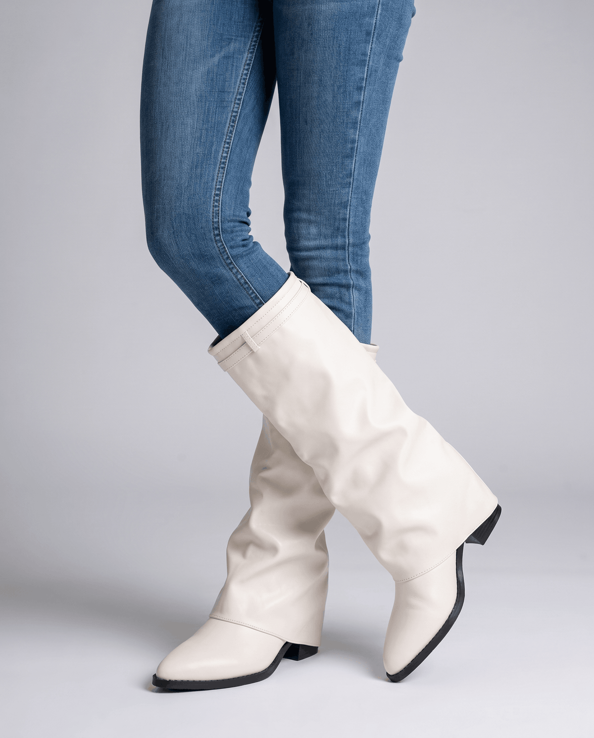 Woman in blue skinny jeans walking in cream slouch boots