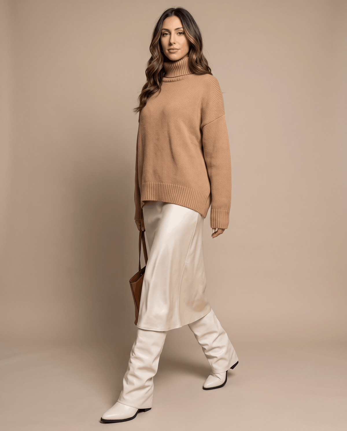 Woman in a camel sweater and satin slip skirt wearing cream boots