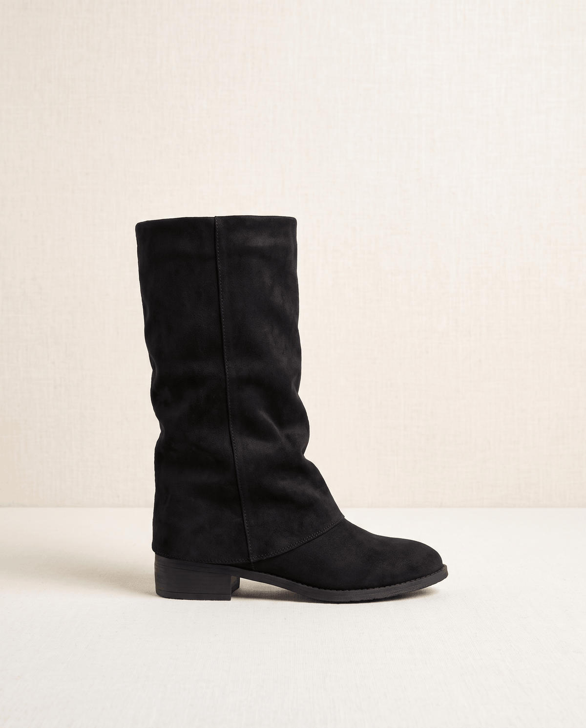 Single black boot in side profile showing the fold-over cuff and block heel