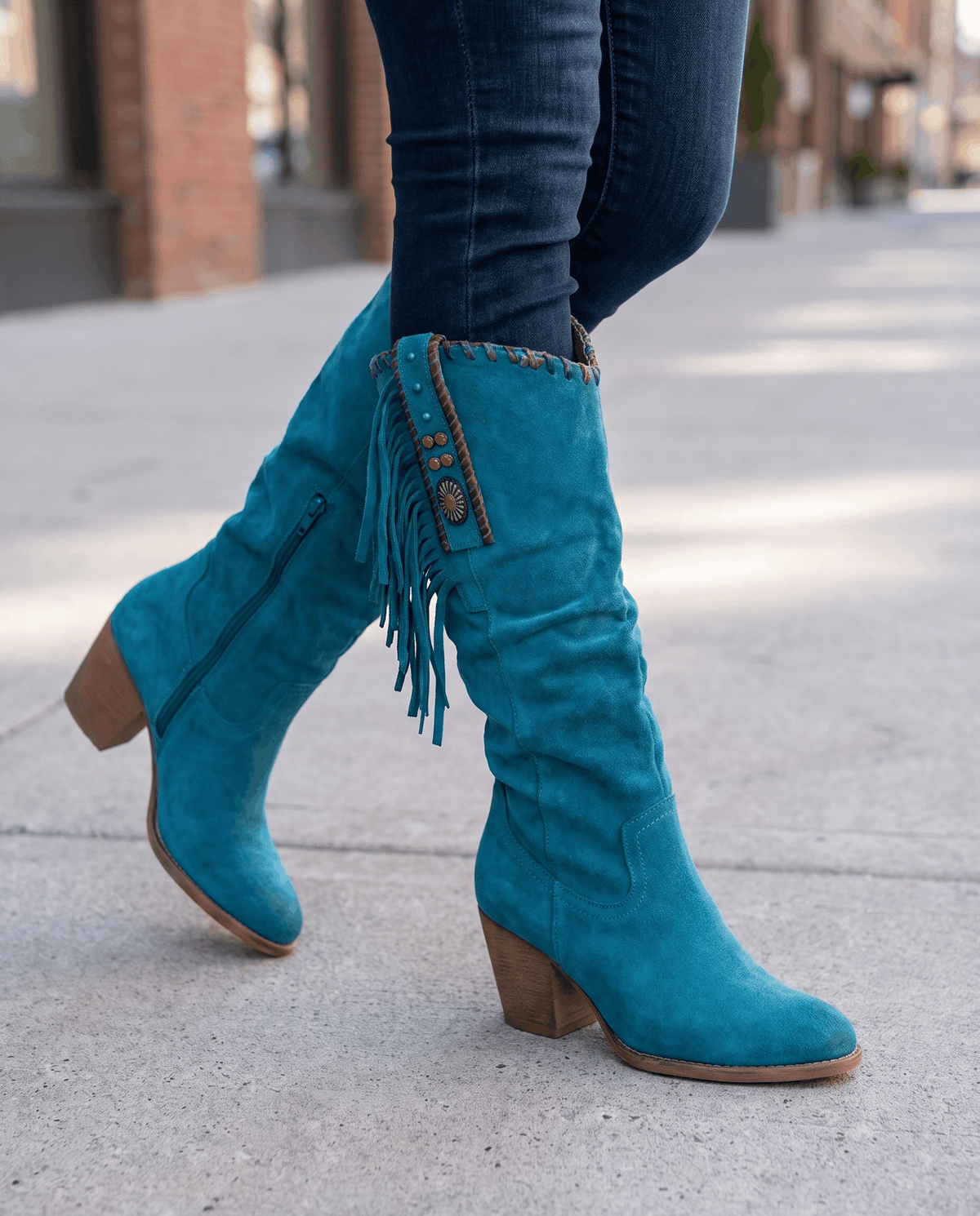 Blue slouchy western boots worn walking on a sunny city sidewalk
