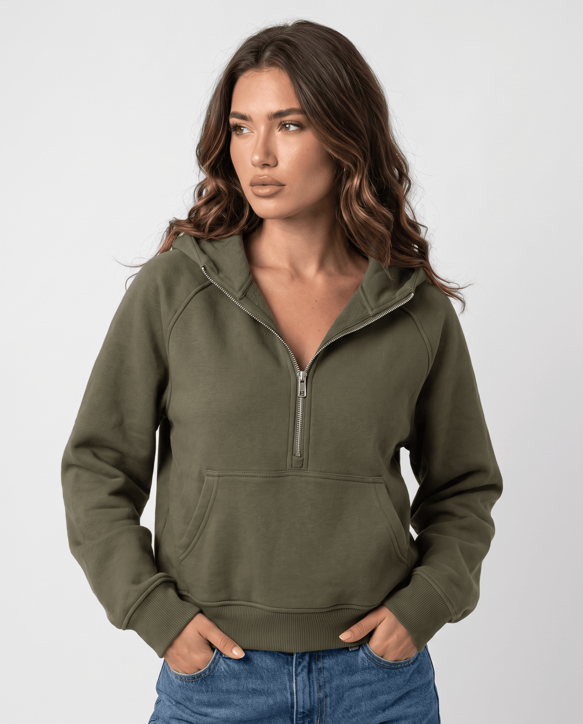 Green cropped half zip hoodie worn with jeans and hands in the pockets, front view