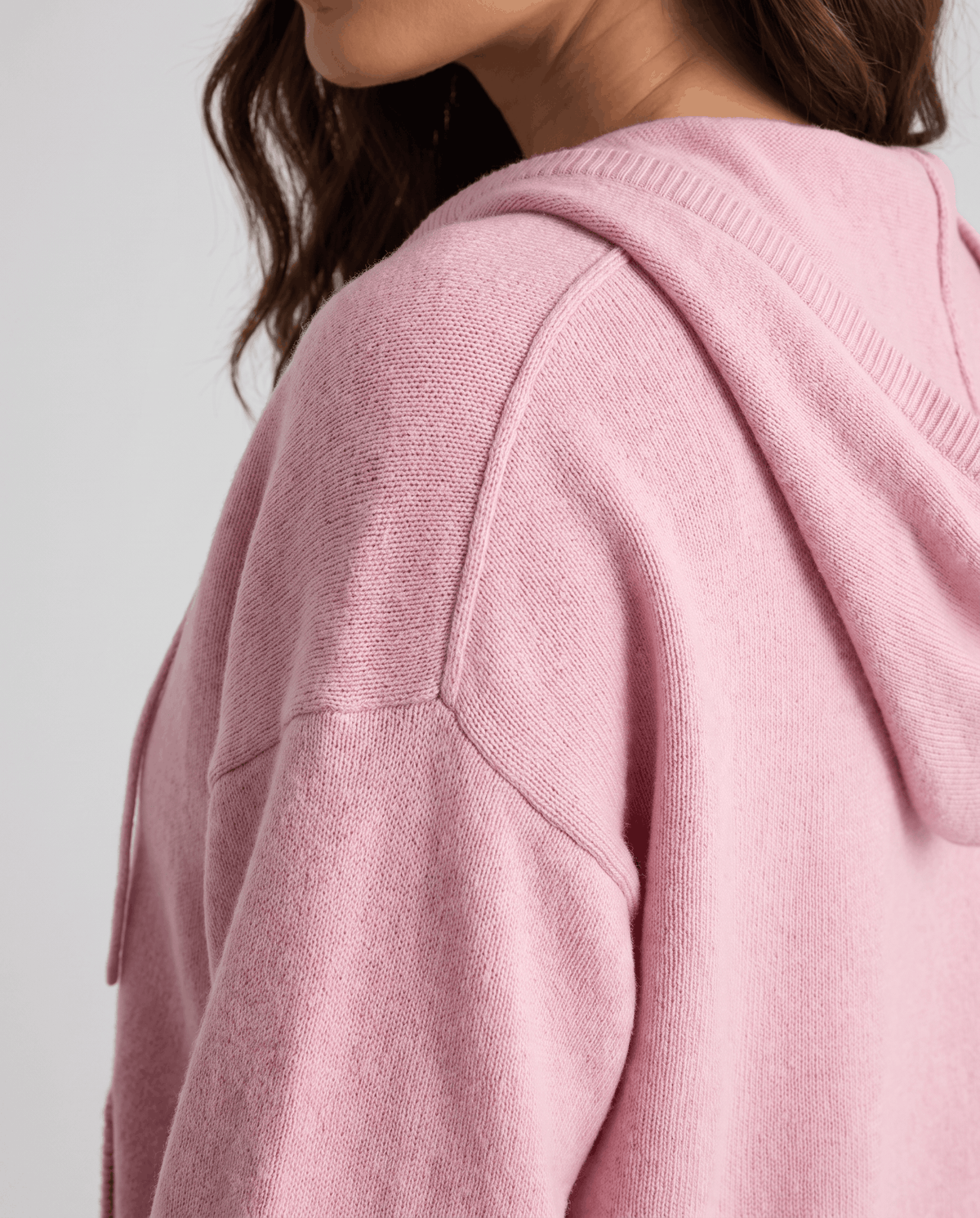 Side close-up of light pink hood and shoulder showing the soft knit fabric
