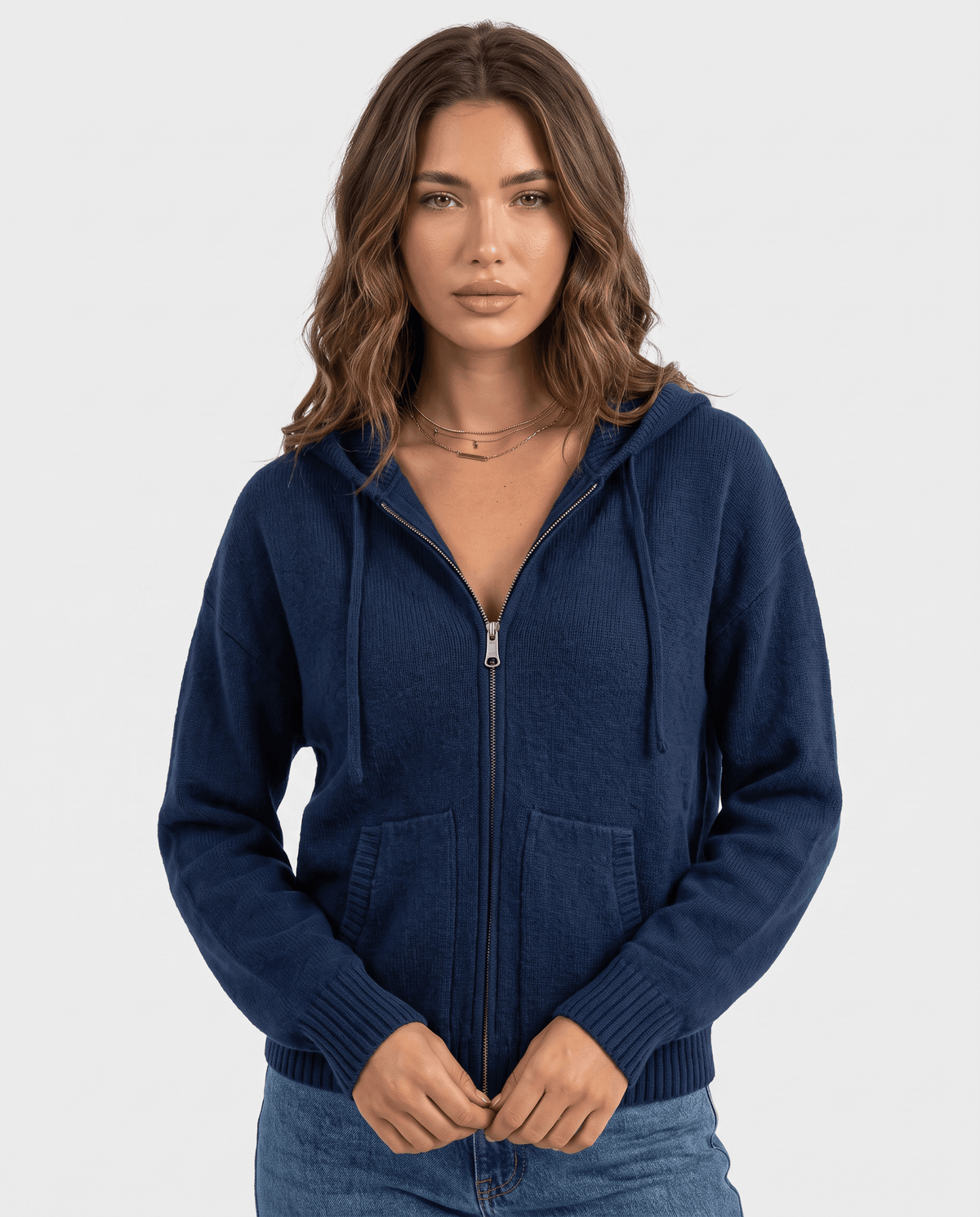 Navy blue hooded knit cardigan zipped up and worn with blue jeans