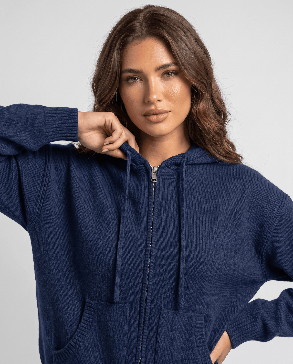 Close-up of navy blue cardigan zip front and hood with a hand on the sleeve