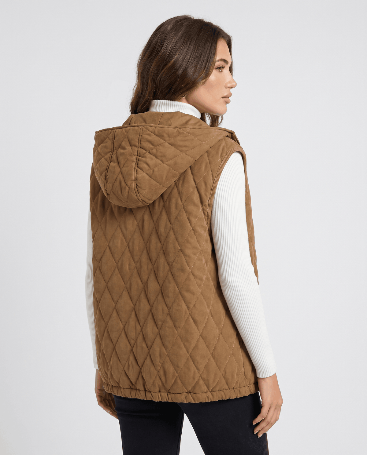 Back view of brown hooded quilted vest worn with black trousers