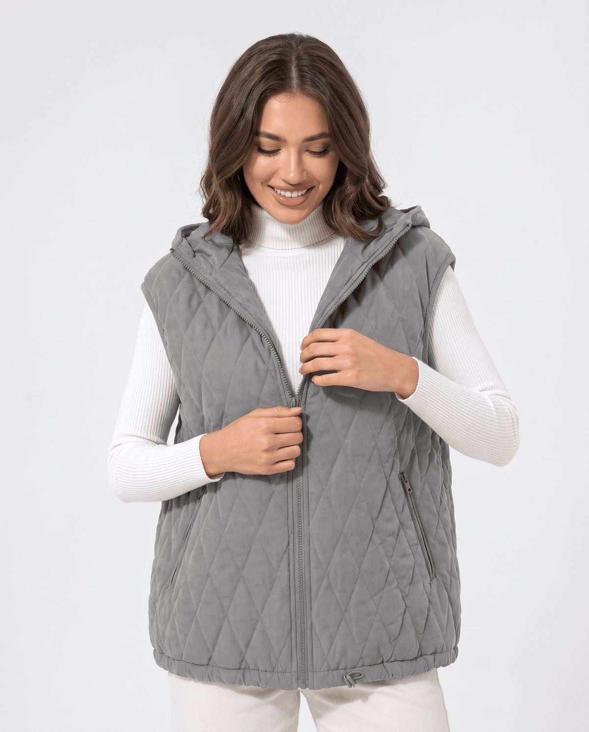 Gray hooded quilted vest with full zip front worn over a white turtleneck