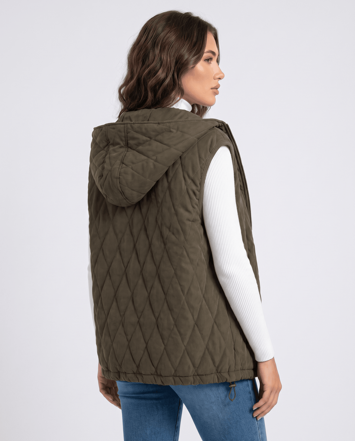 Back view of green hooded quilted vest worn with blue jeans