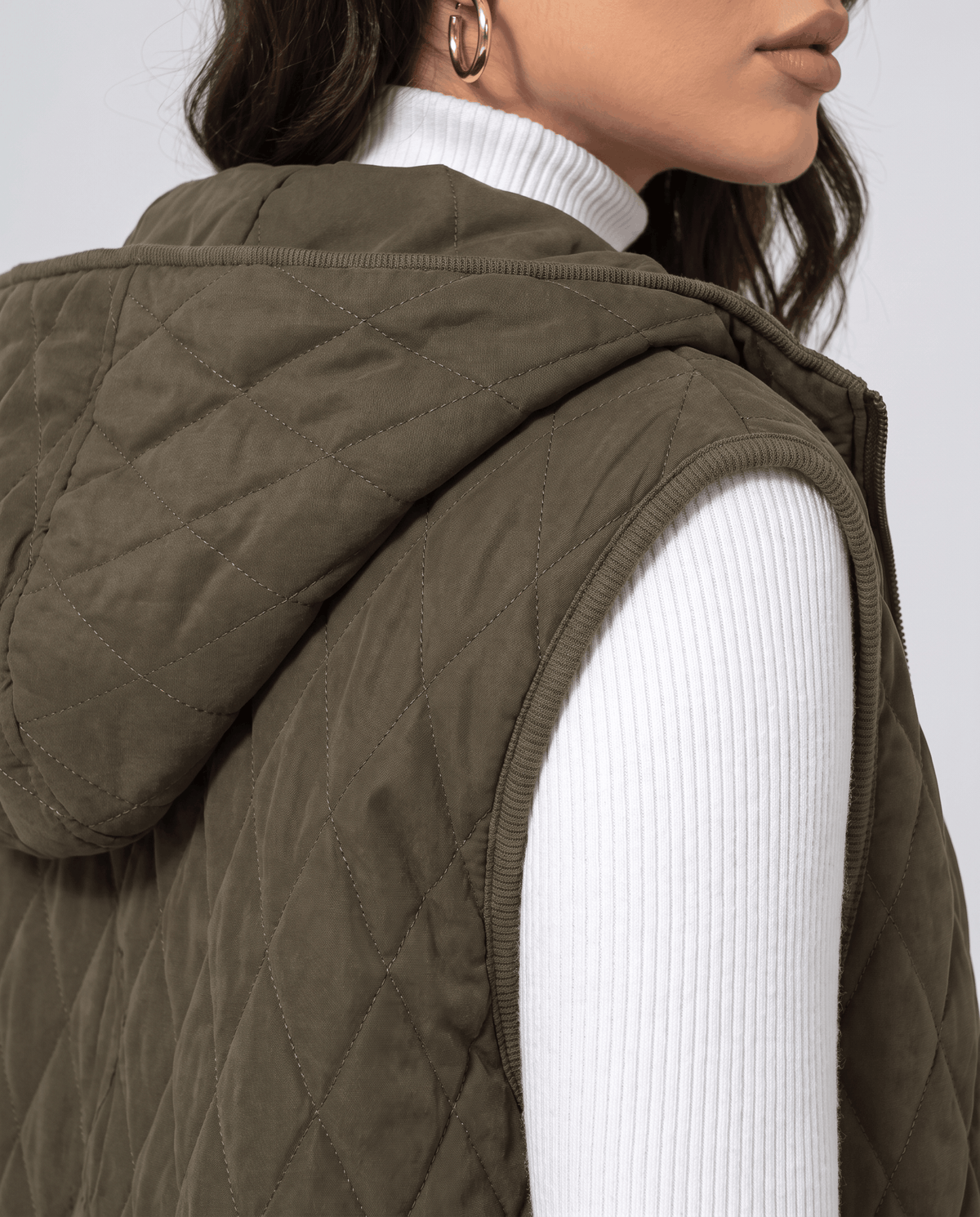 Close view of green quilted vest attached hood and stitching