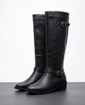 Black knee-high riding boots with structured shafts, antique brass buckle straps, pointed toes, and stacked block heels.