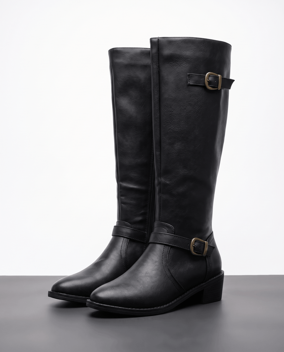 Black knee-high riding boots with structured shafts, antique brass buckle straps, pointed toes, and stacked block heels.