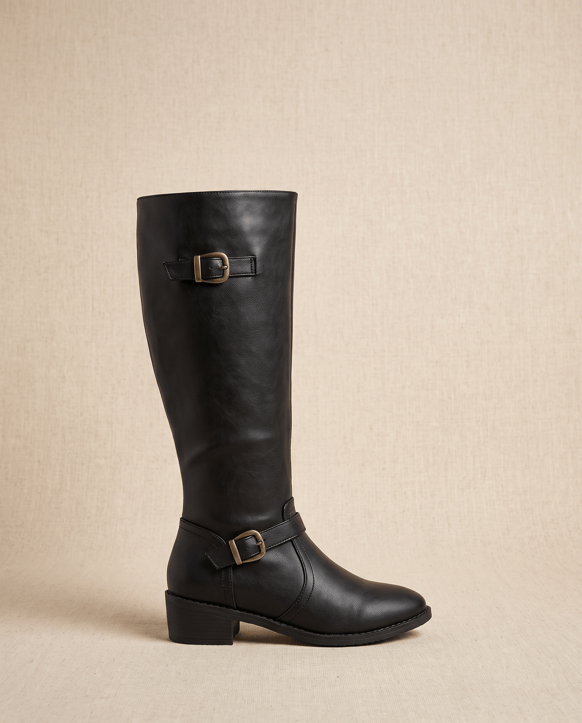 Black knee-high riding boots with structured shafts, antique brass buckles at the cuff and ankle, and a stacked block heel.