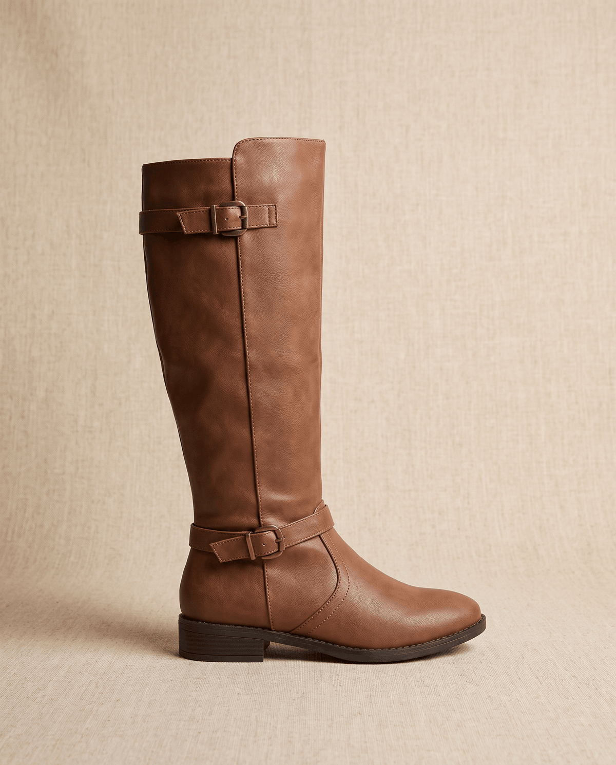 Brown knee-high riding boots with structured shafts, antique brass buckle straps, and a low stacked block heel.