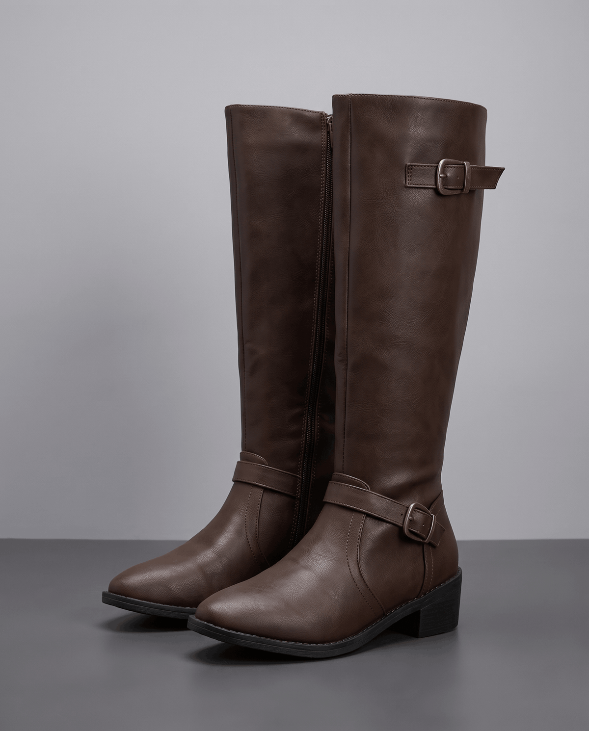 Dark brown knee-high riding boots with structured shafts, antique brass buckle straps, and a stacked block heel.
