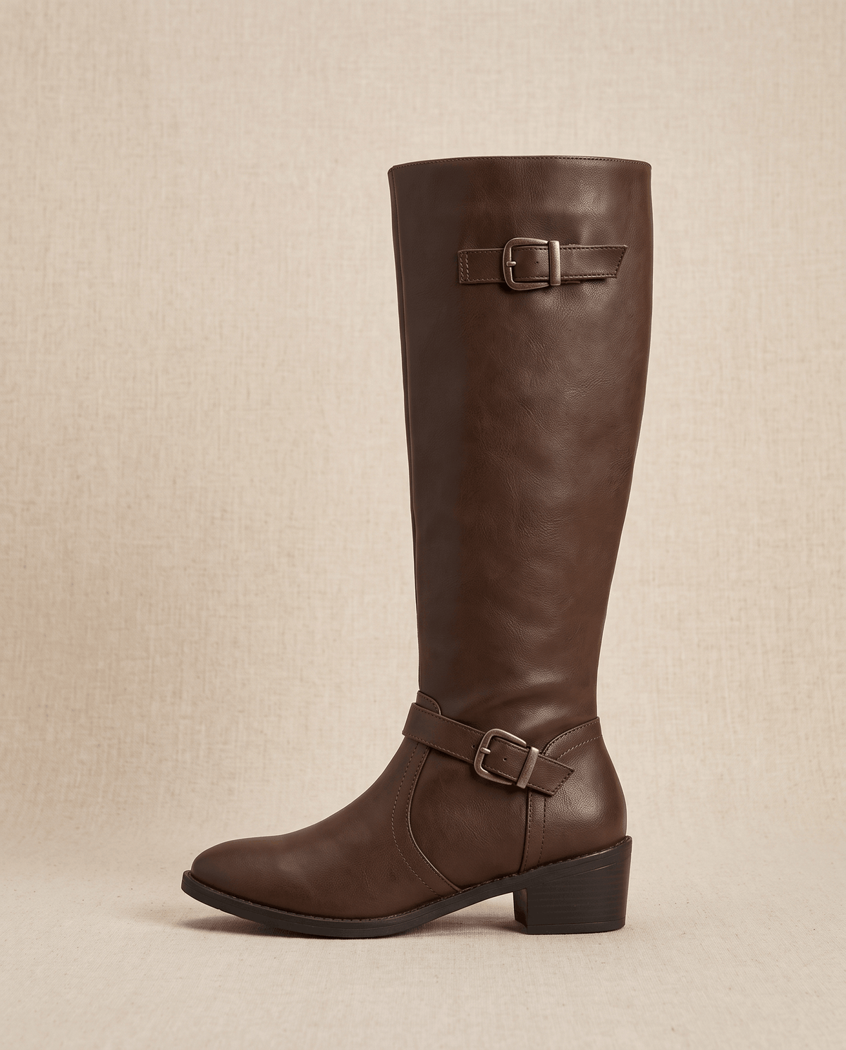 Dark brown knee-high riding boot with a structured shaft, antique brass buckle straps, and a stacked block heel.