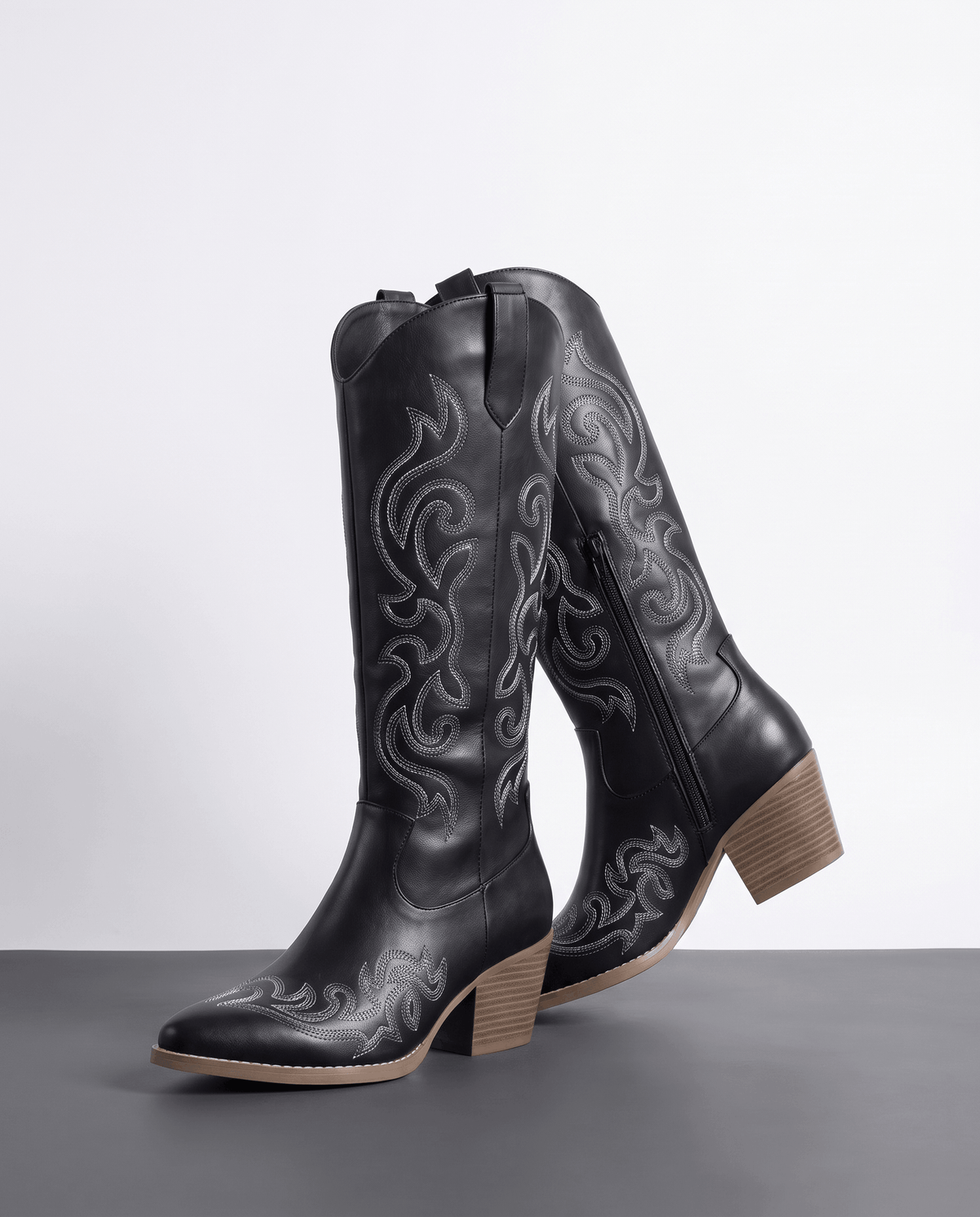 Black pair angled on a gray floor showing gray scroll embroidery and stacked heel