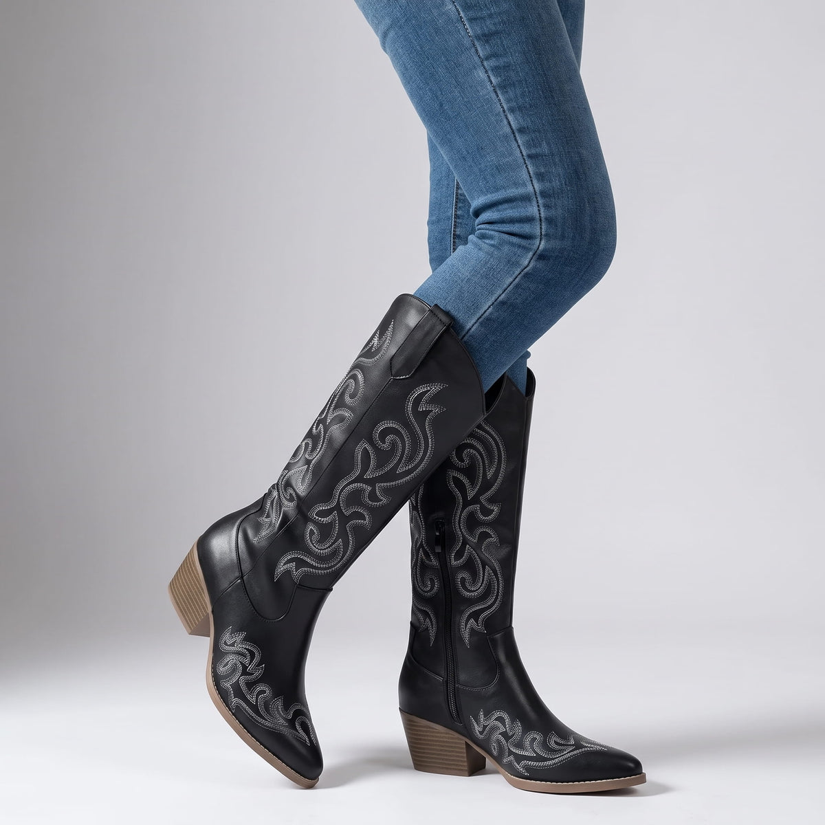 Woman in blue skinny jeans walking in black embroidered boots