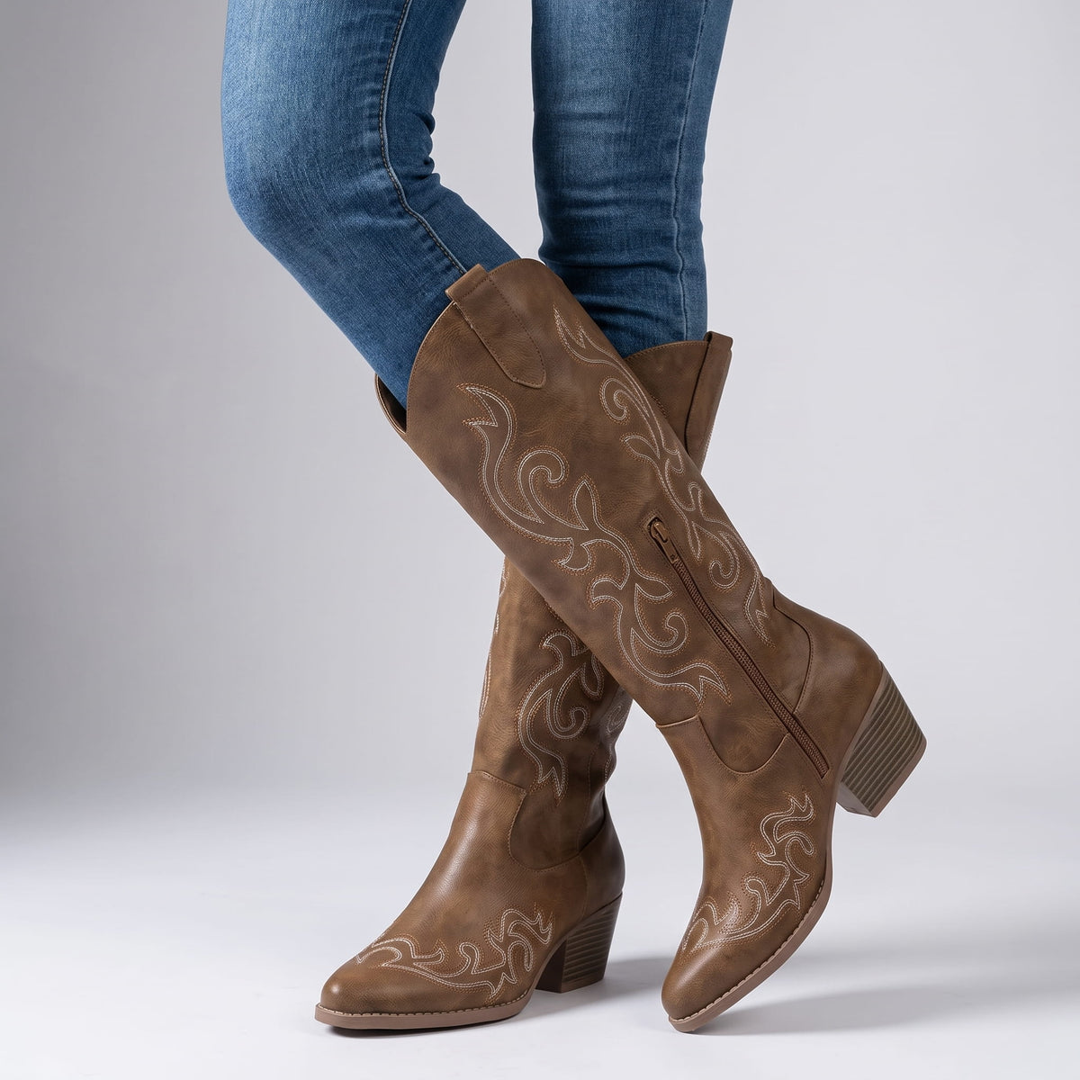 Woman in blue skinny jeans walking in brown embroidered boots