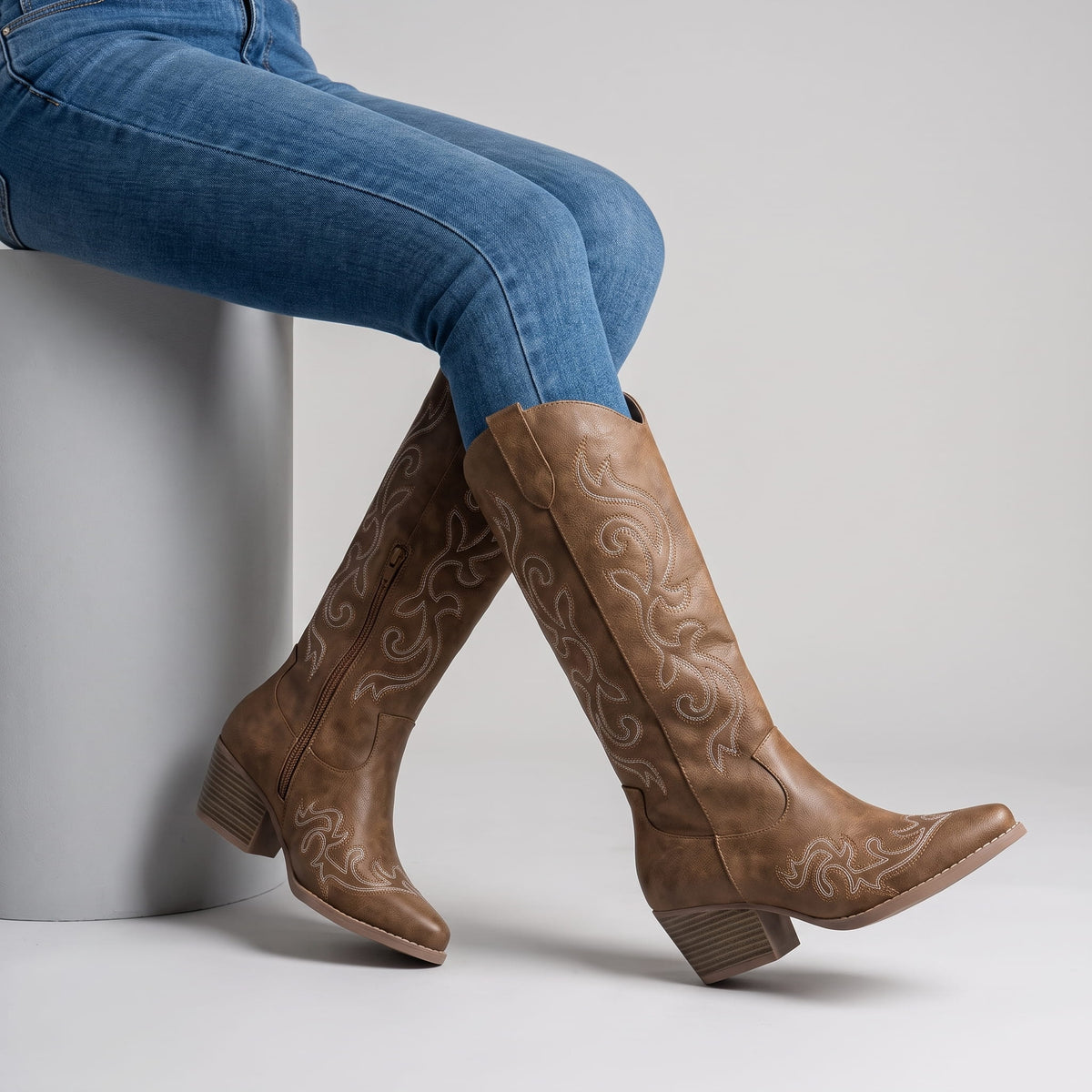 Seated woman in jeans with crossed legs wearing brown western boots