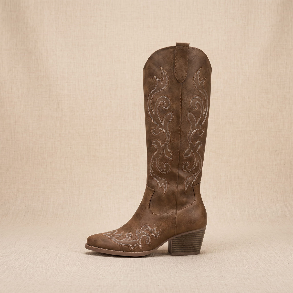 Single brown boot in side profile on a beige backdrop