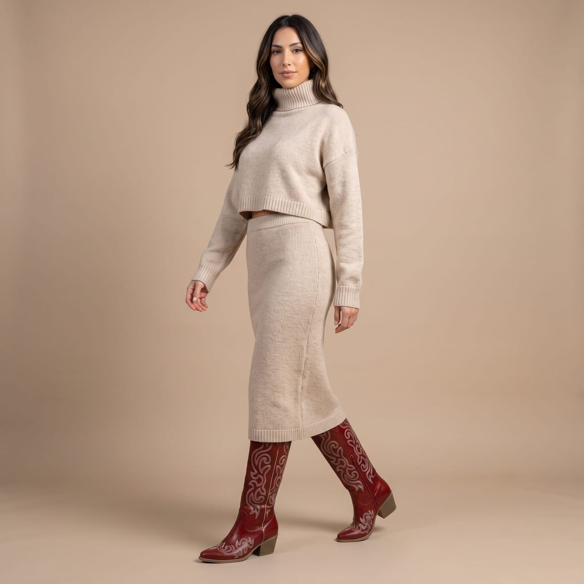 Woman in a beige knit sweater and skirt set styled with red cowboy boots