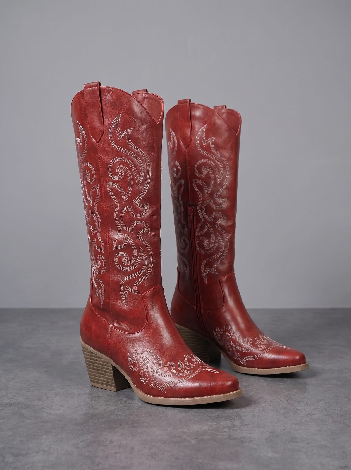Leather embroidered cowboy boots in red on a dark floor with a stacked block heel