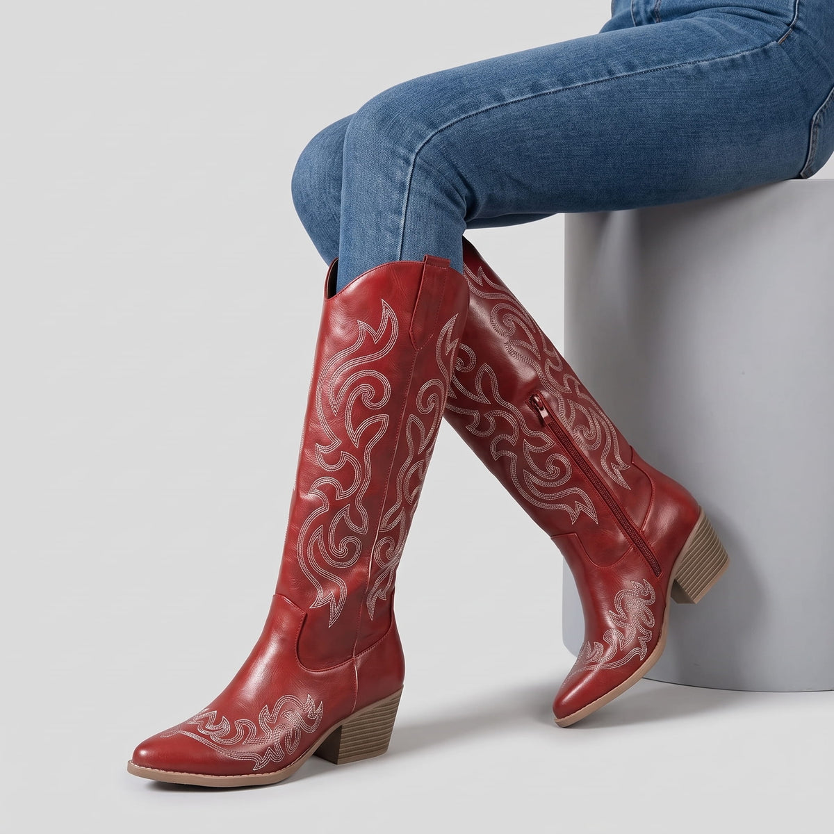 Seated woman in jeans with crossed legs wearing red western boots
