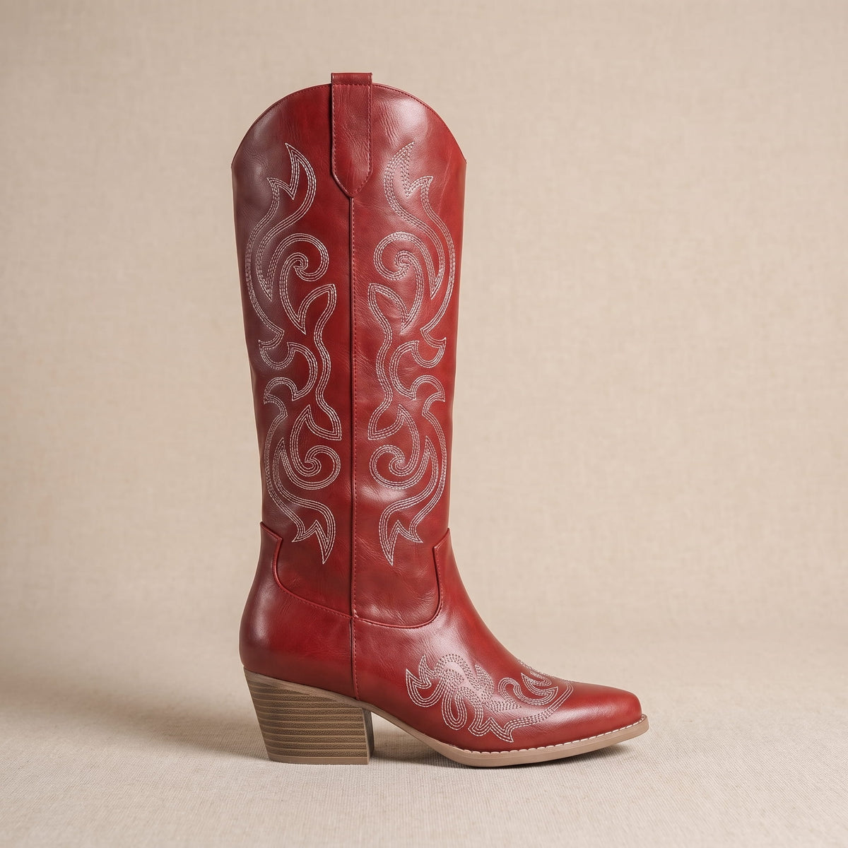 Single red boot in side profile on a beige backdrop