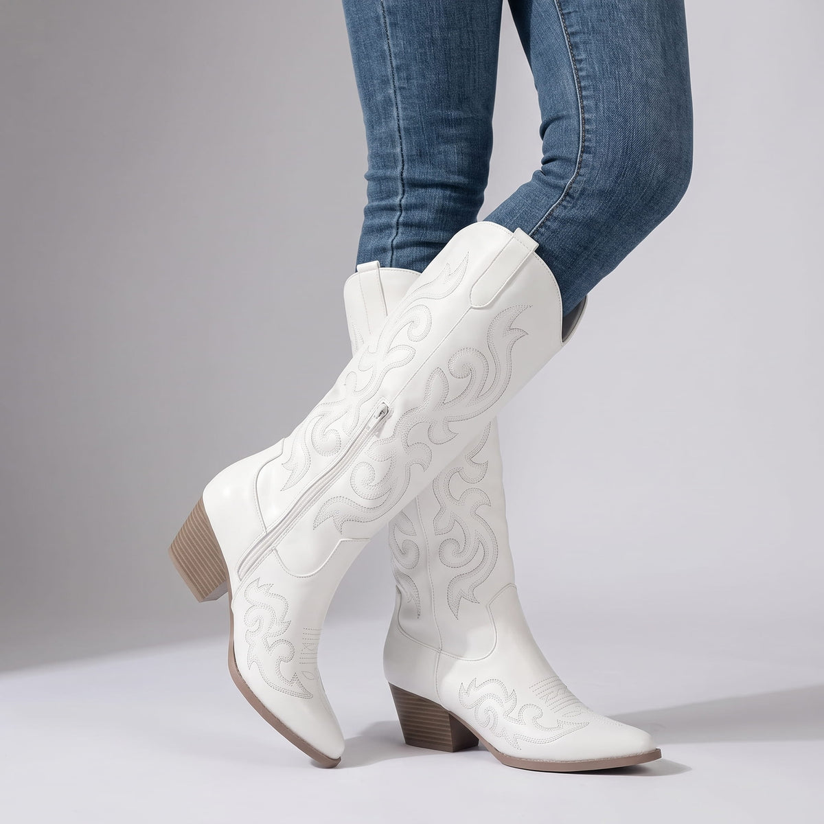 Woman in jeans wearing white boots with the inside zip visible