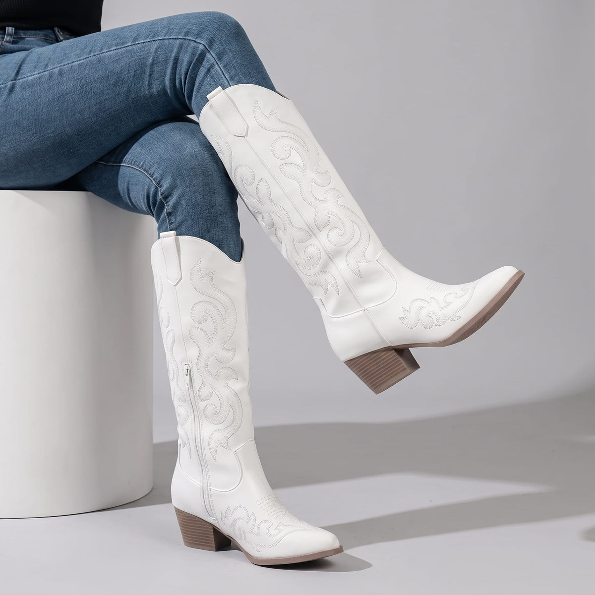 Seated woman in jeans with crossed legs wearing white western boots