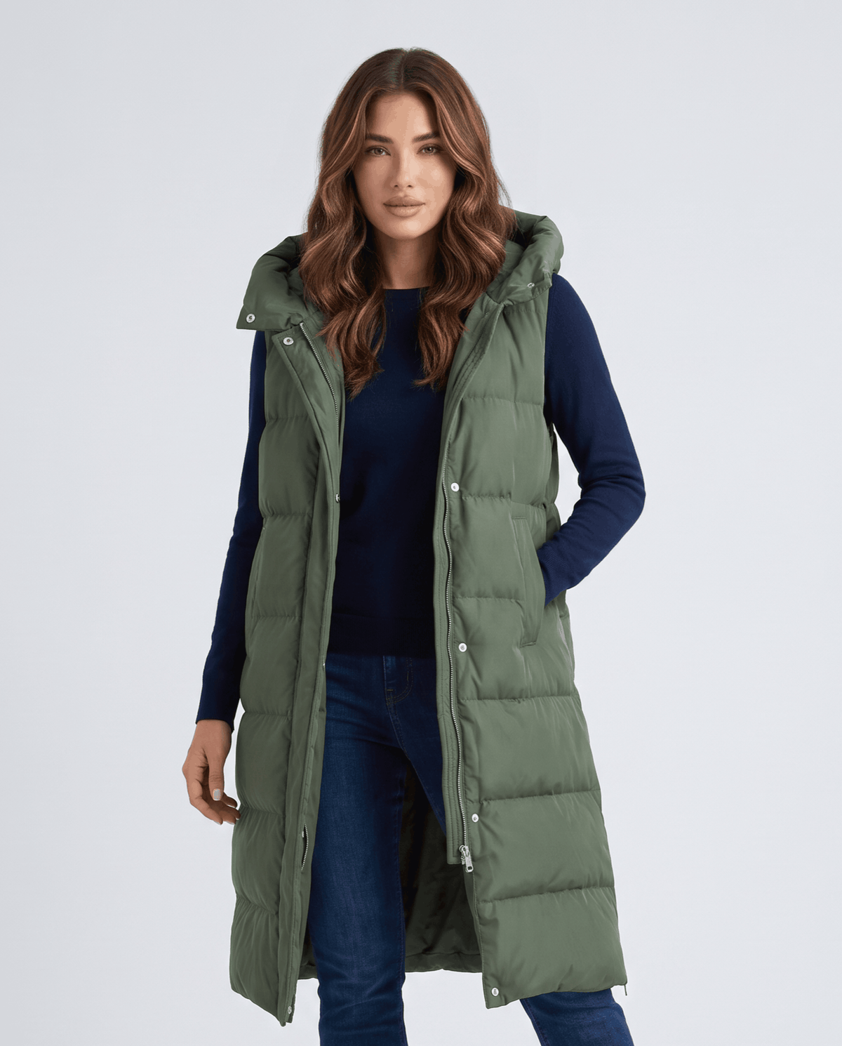 Women's army green long quilted hooded vest worn over a navy sweater and jeans