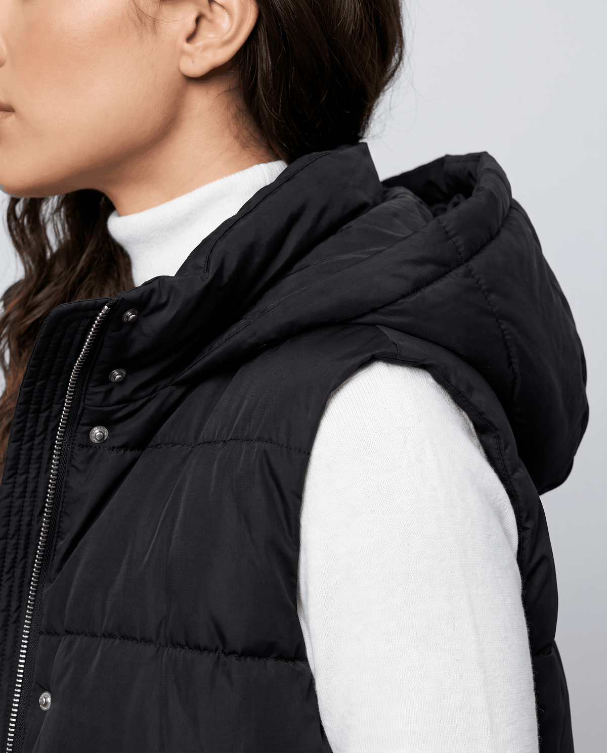 Black quilted vest hood and quilted body shown up close on a model