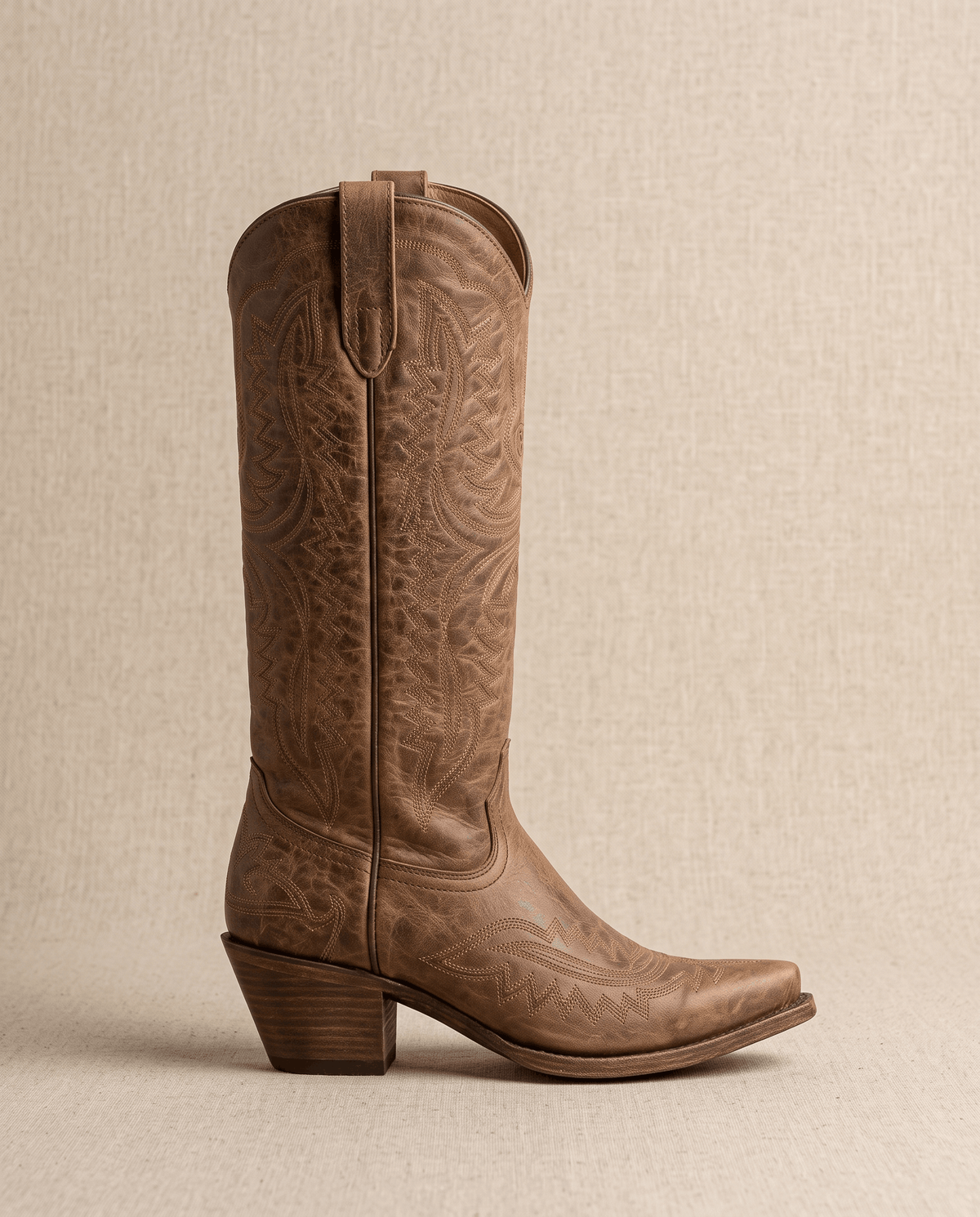 Side profile of a single dark brown boot showing the scalloped top and wood-tone heel