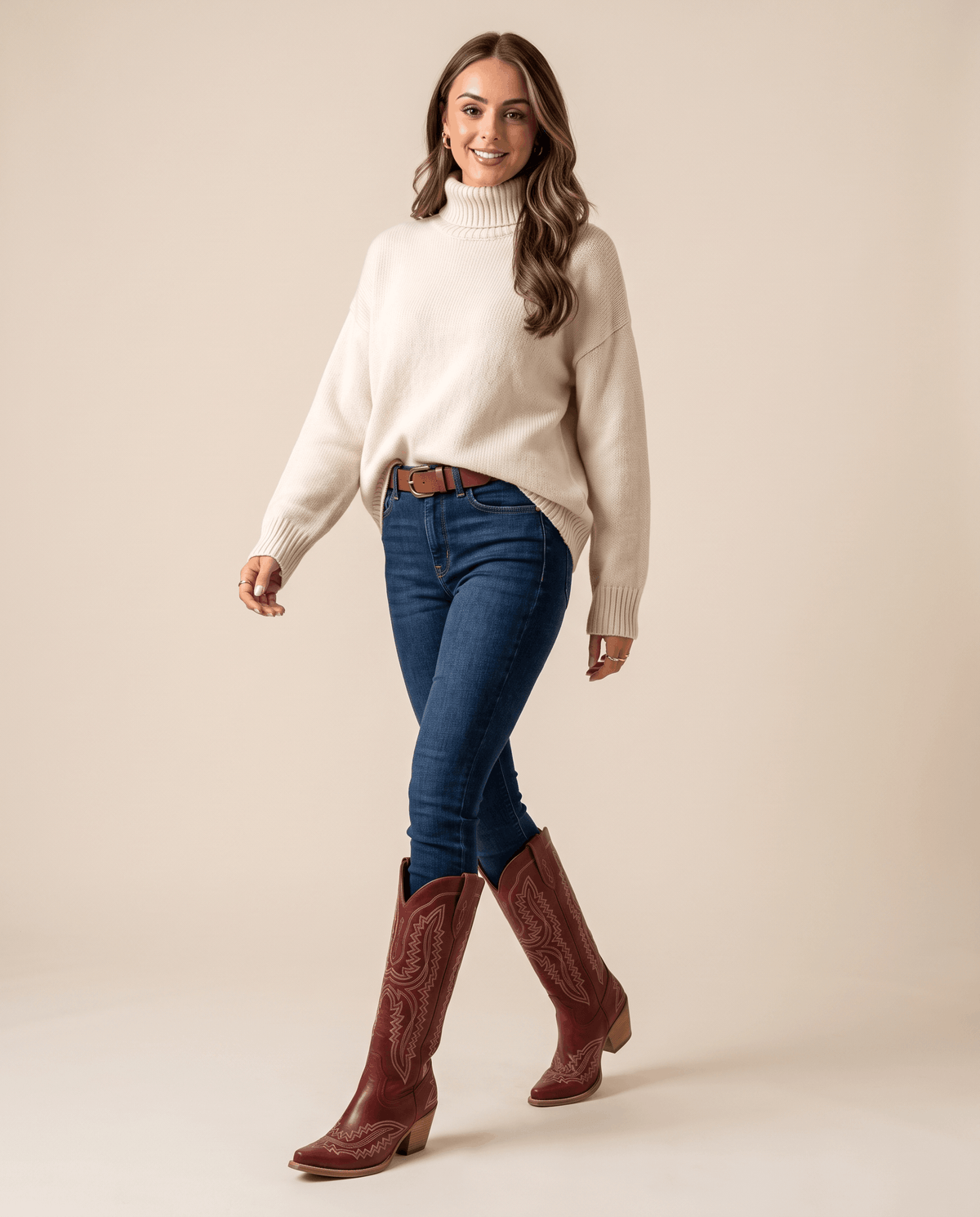 Woman in a white sweater and jeans tucked into red embroidered western boots