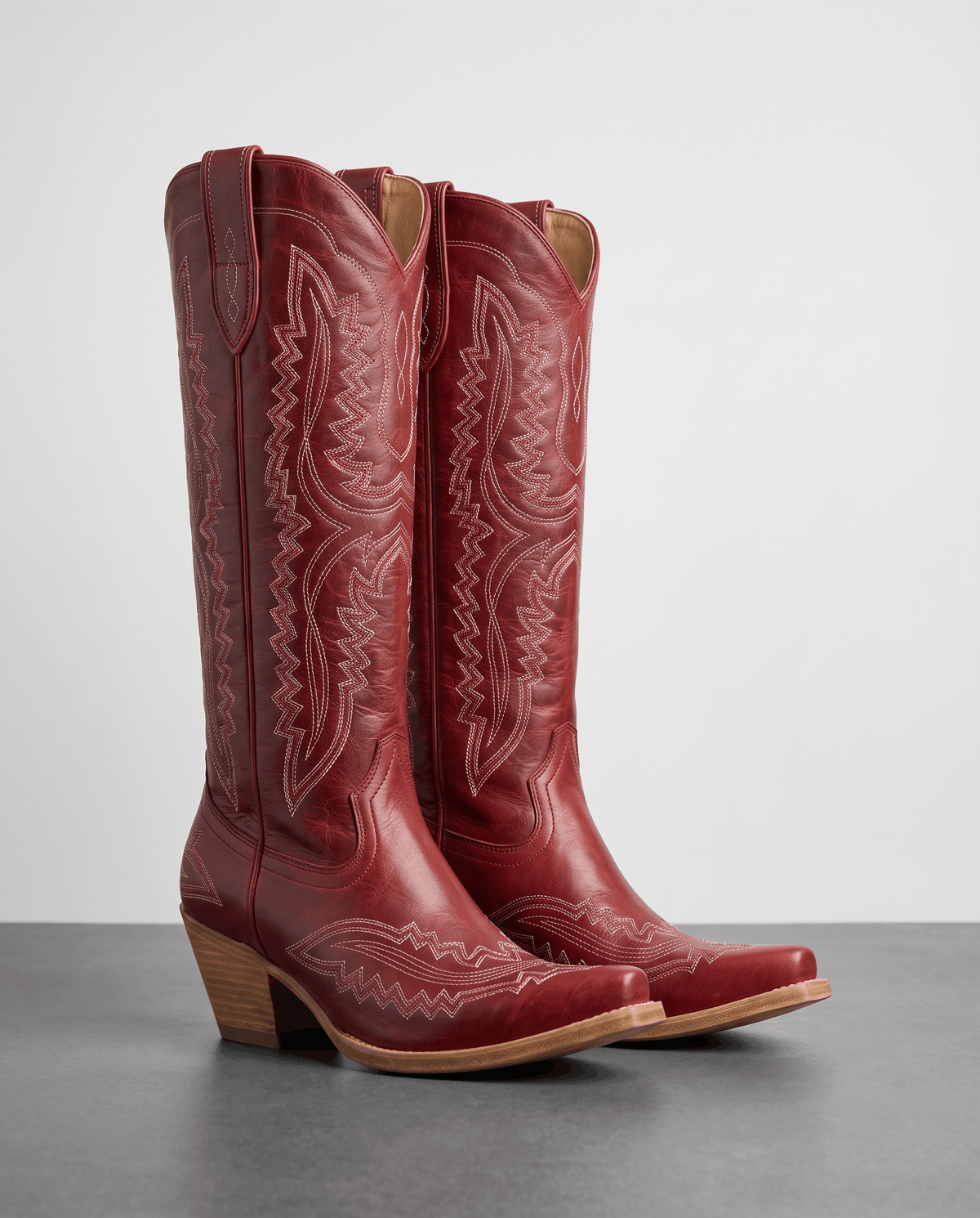 Pair of red leather western boots with tonal scroll stitching and wood-tone heels