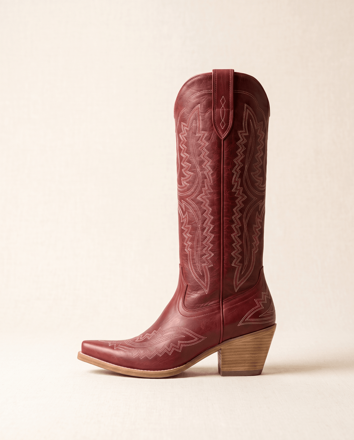 Single red cowboy boot in side profile showing the pointed toe and stacked heel