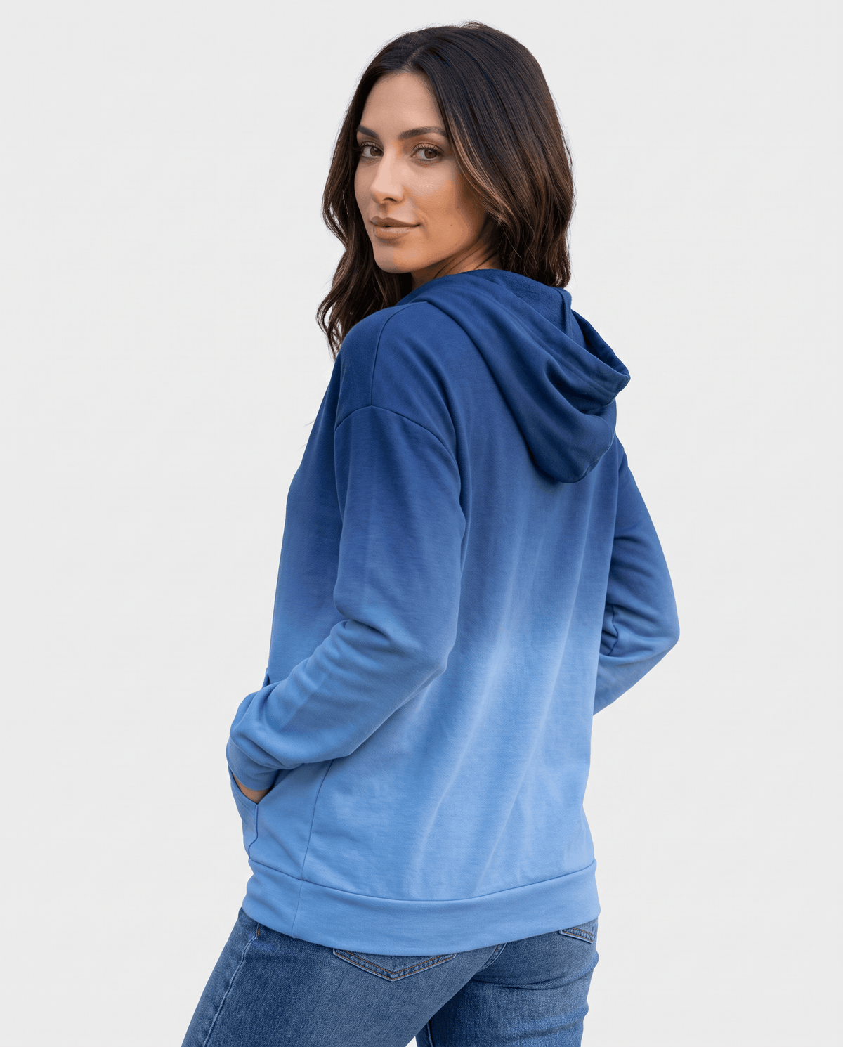 Back angle of the blue ombre pullover with the hood down and a hand in the pocket