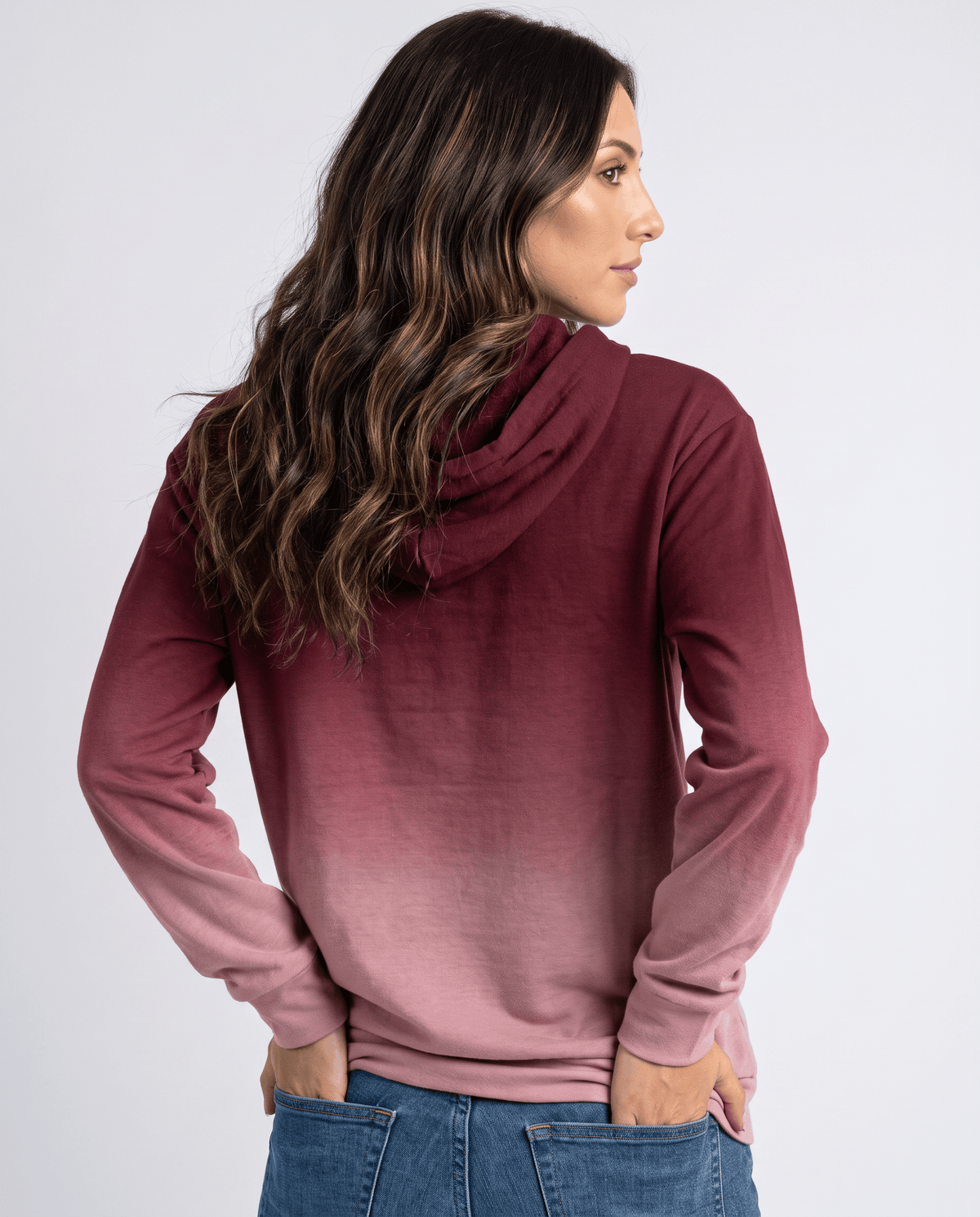 Back view of the burgundy ombre pullover with hands in jeans pockets