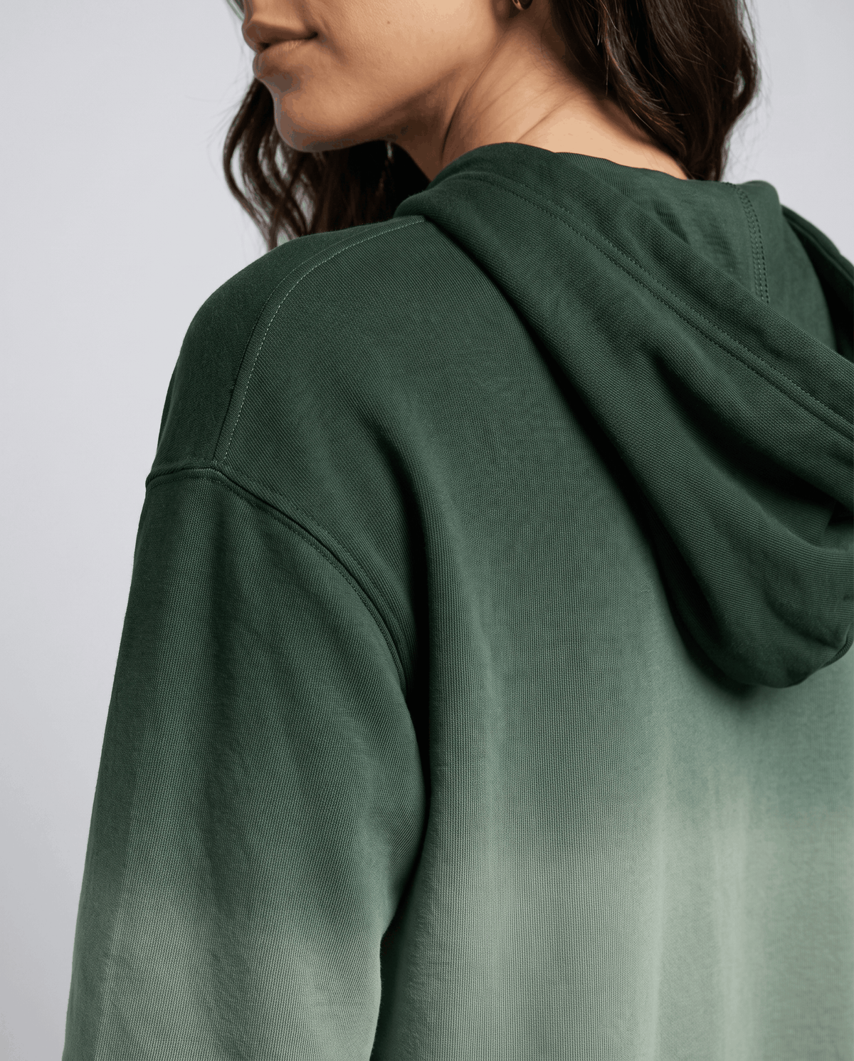 Side close-up of the green hood and raglan sleeve with the gradient fade