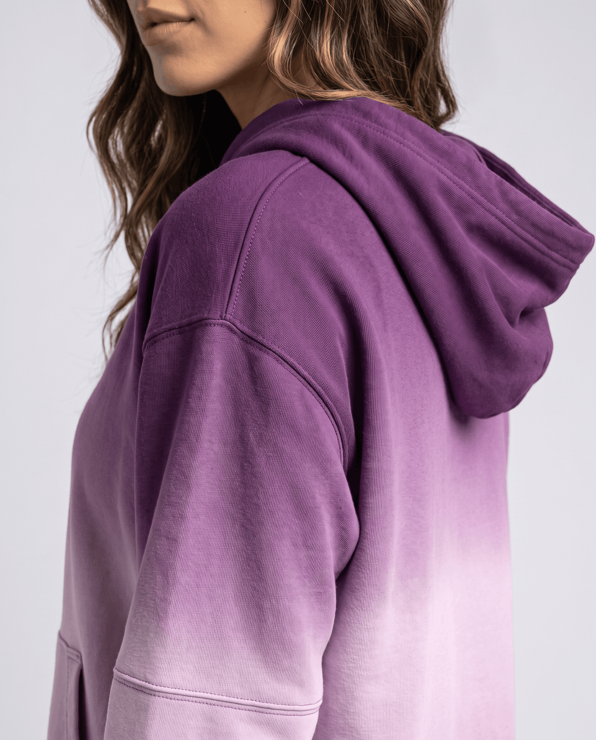 Side close-up of the purple hood and ribbed sleeve texture with a soft fade