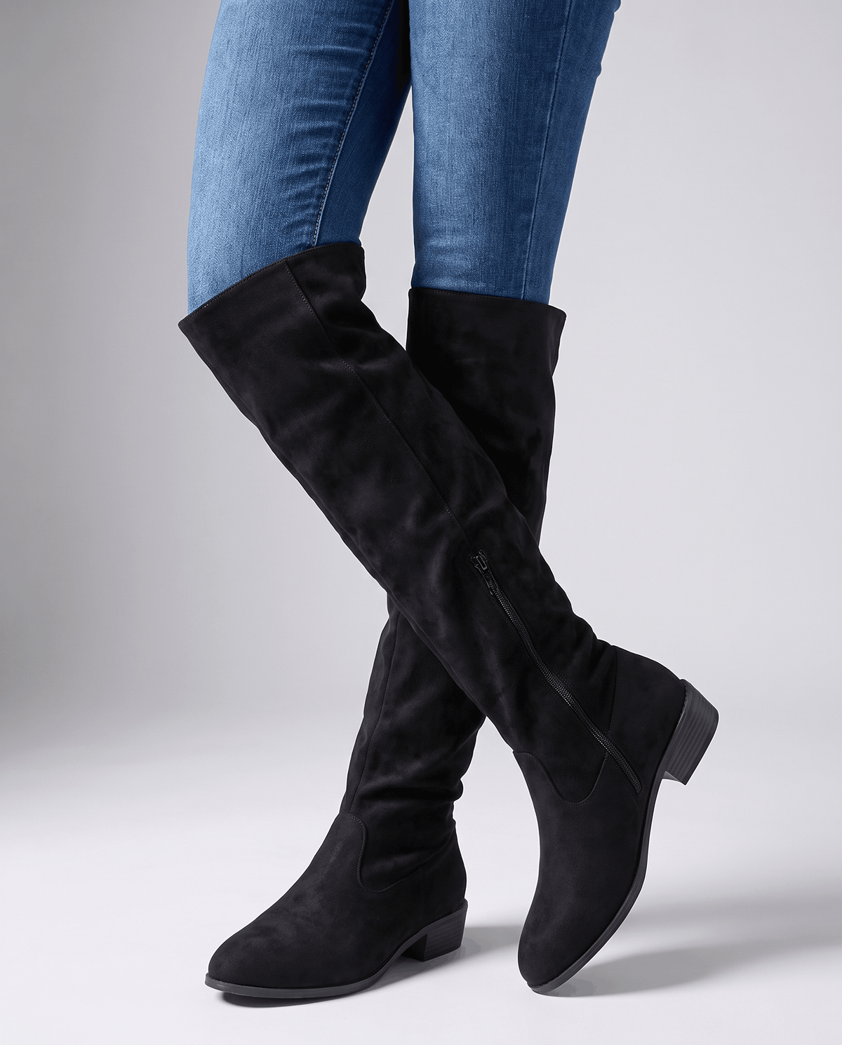 Woman in skinny jeans walking in black suede boots above the knee