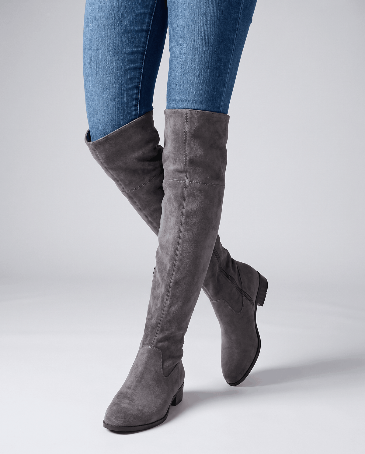 Woman in blue jeans walking in tall gray suede boots