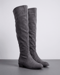 Over-the-knee slouch boots in gray suede on a dark floor showing the tall shaft and low heel