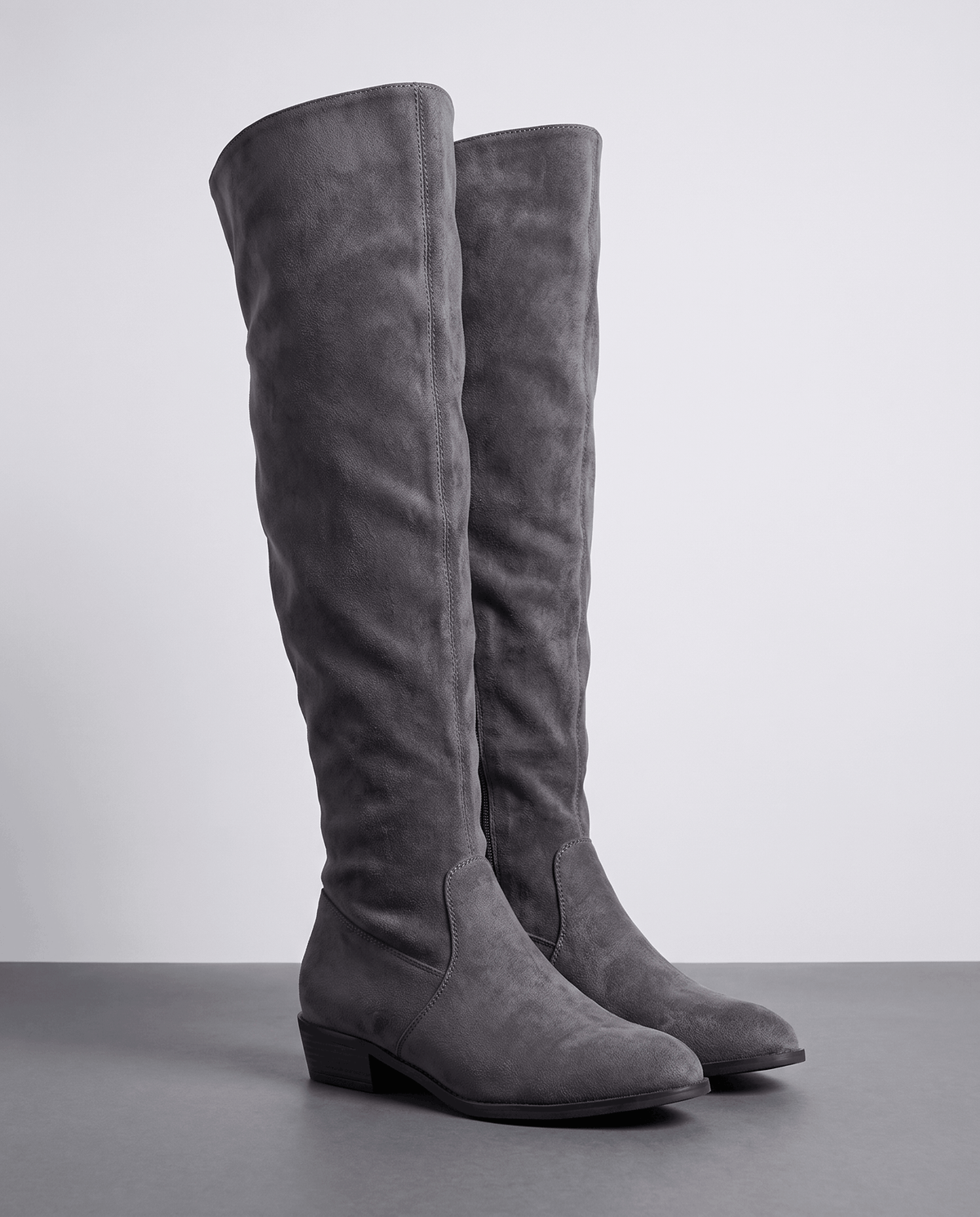 Over-the-knee slouch boots in gray suede on a dark floor showing the tall shaft and low heel