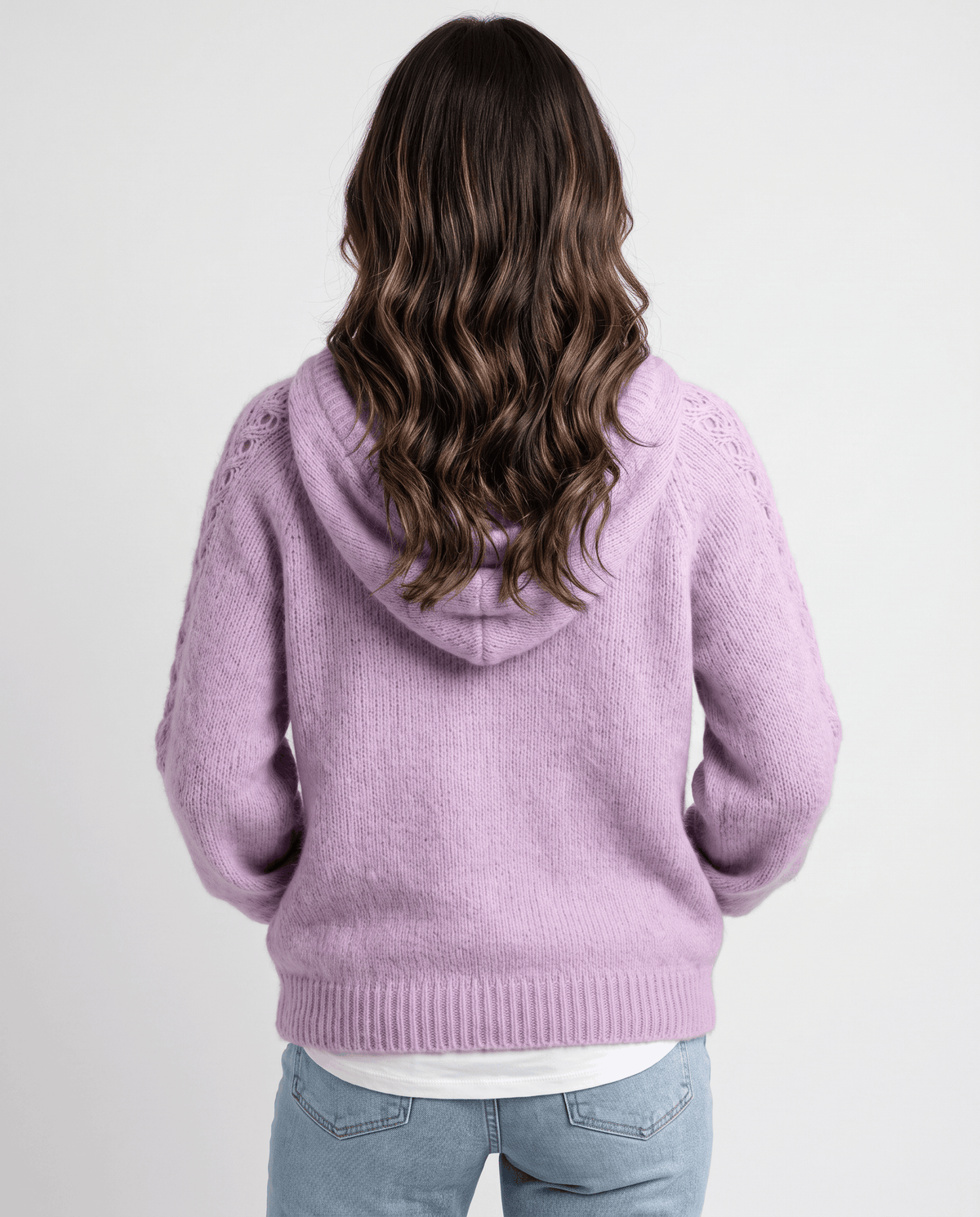 Back view of the purple knit sweater with the hood down over a white layer and jeans