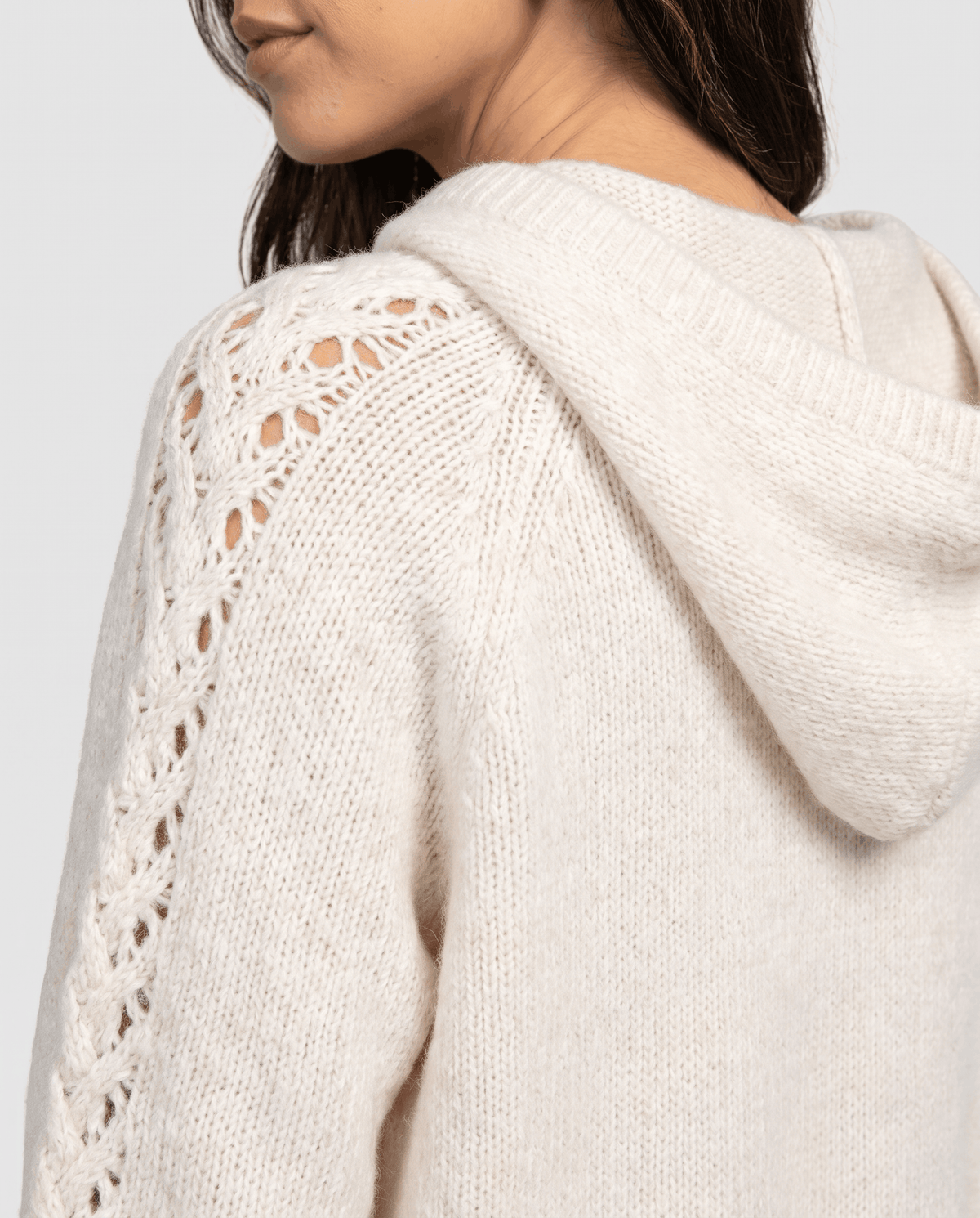 Side close-up of the white hood and open-stitch sleeve detail