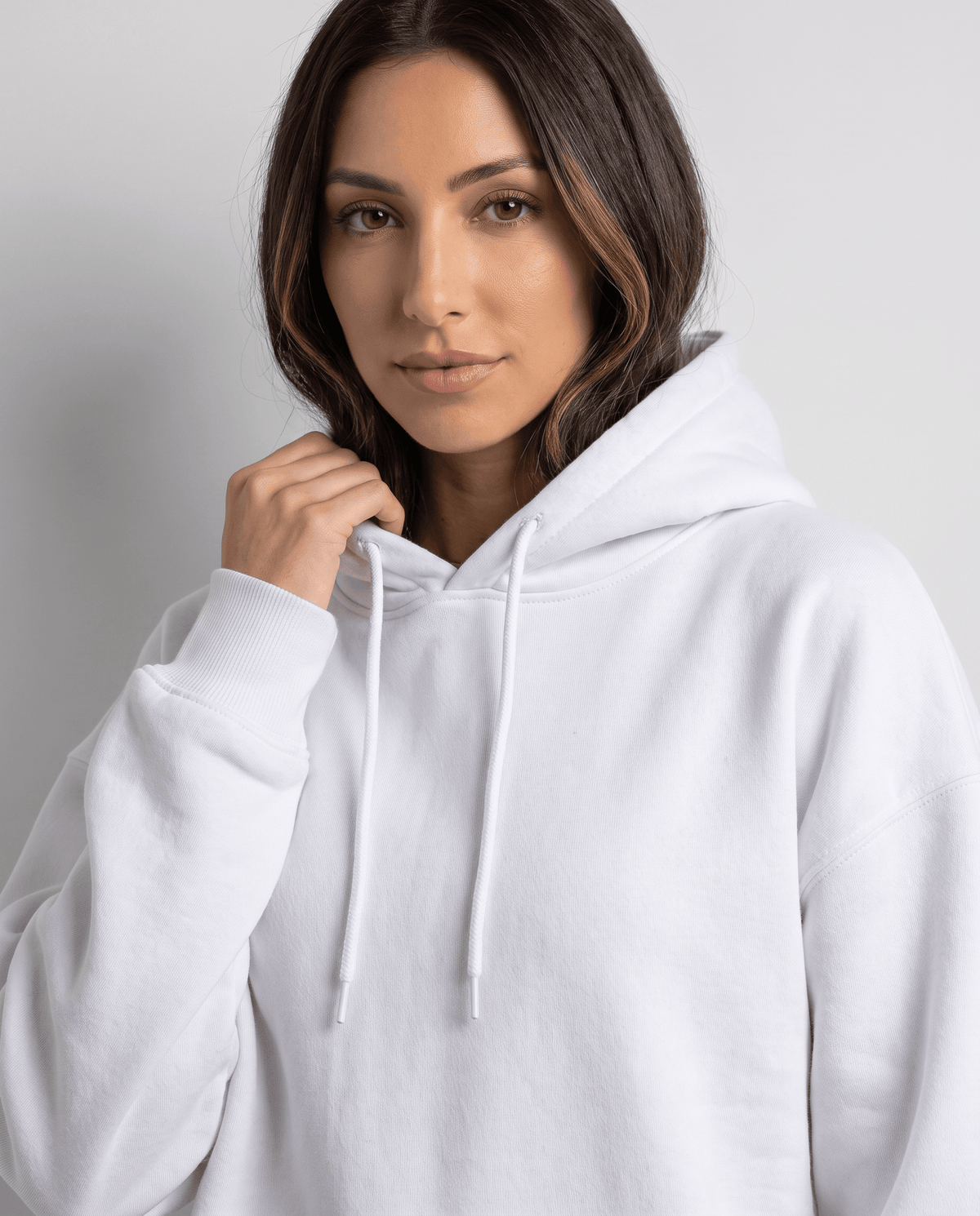 Close-up of the white hood and drawstrings with a hand resting at the collar
