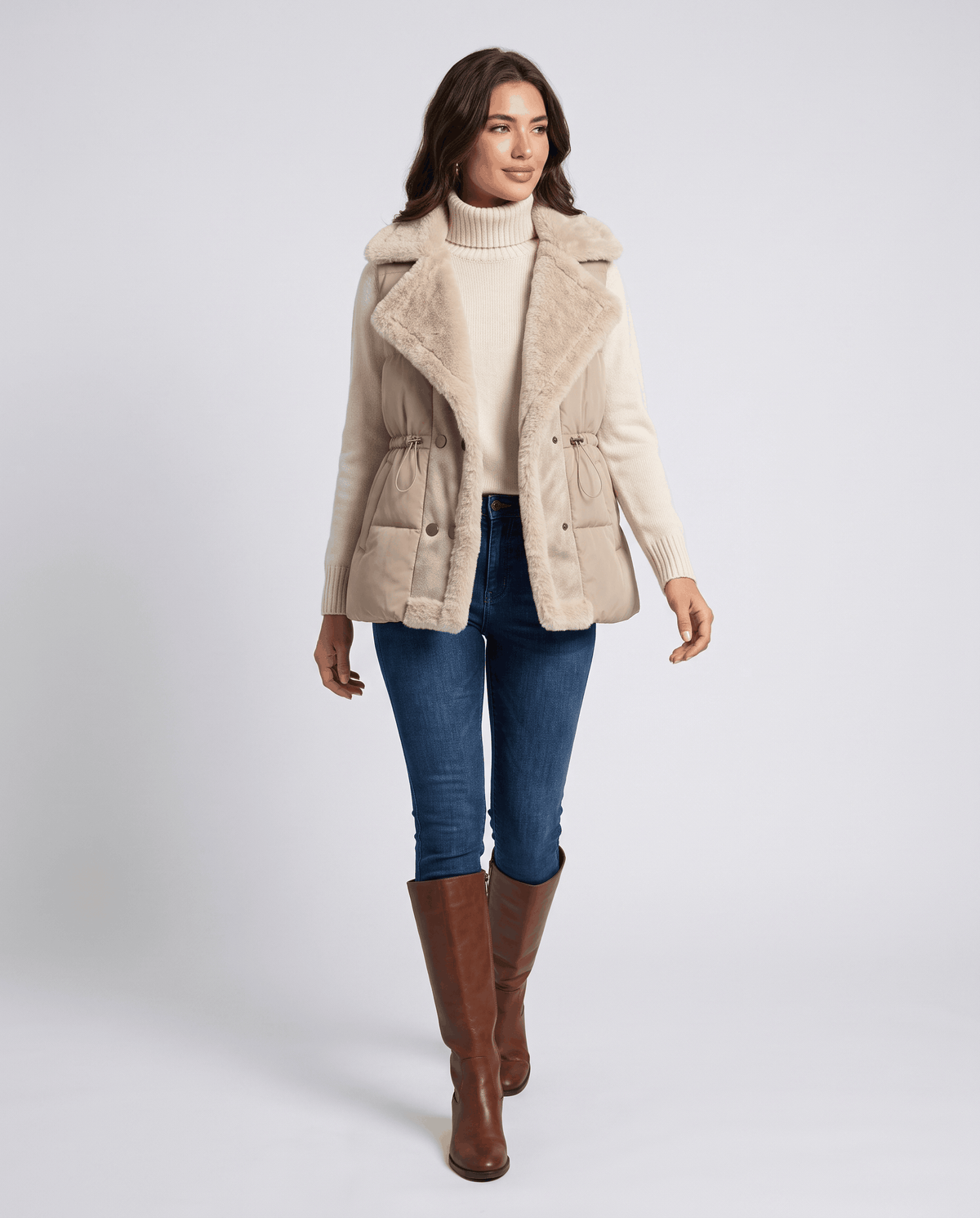 Full-length look with brown padded vest, blue jeans and brown boots