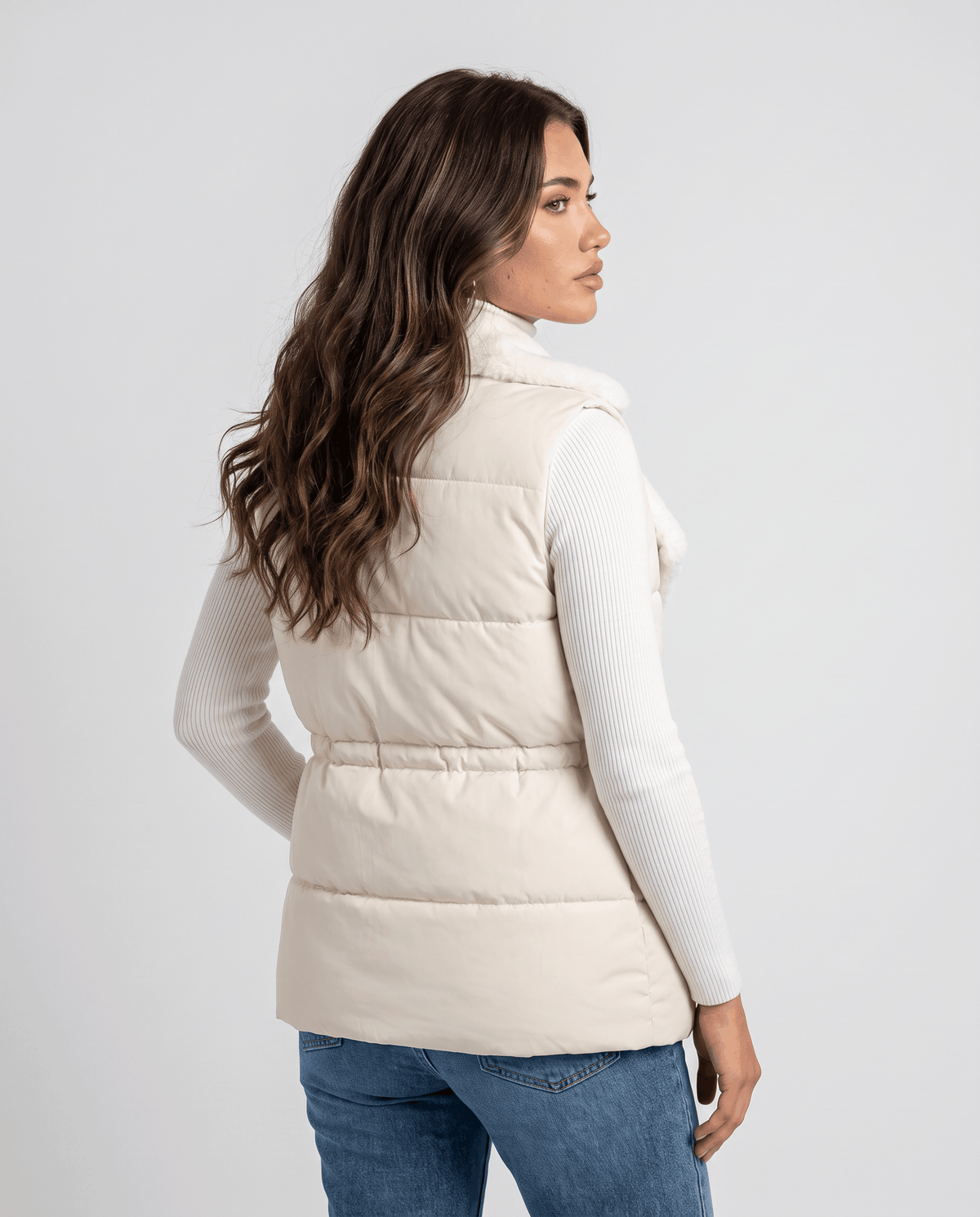 Back view of ivory padded vest worn over a white top