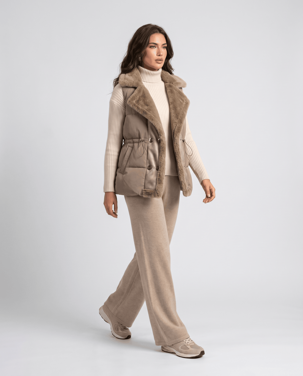 Full-length look with khaki padded vest, cream knit and beige trousers