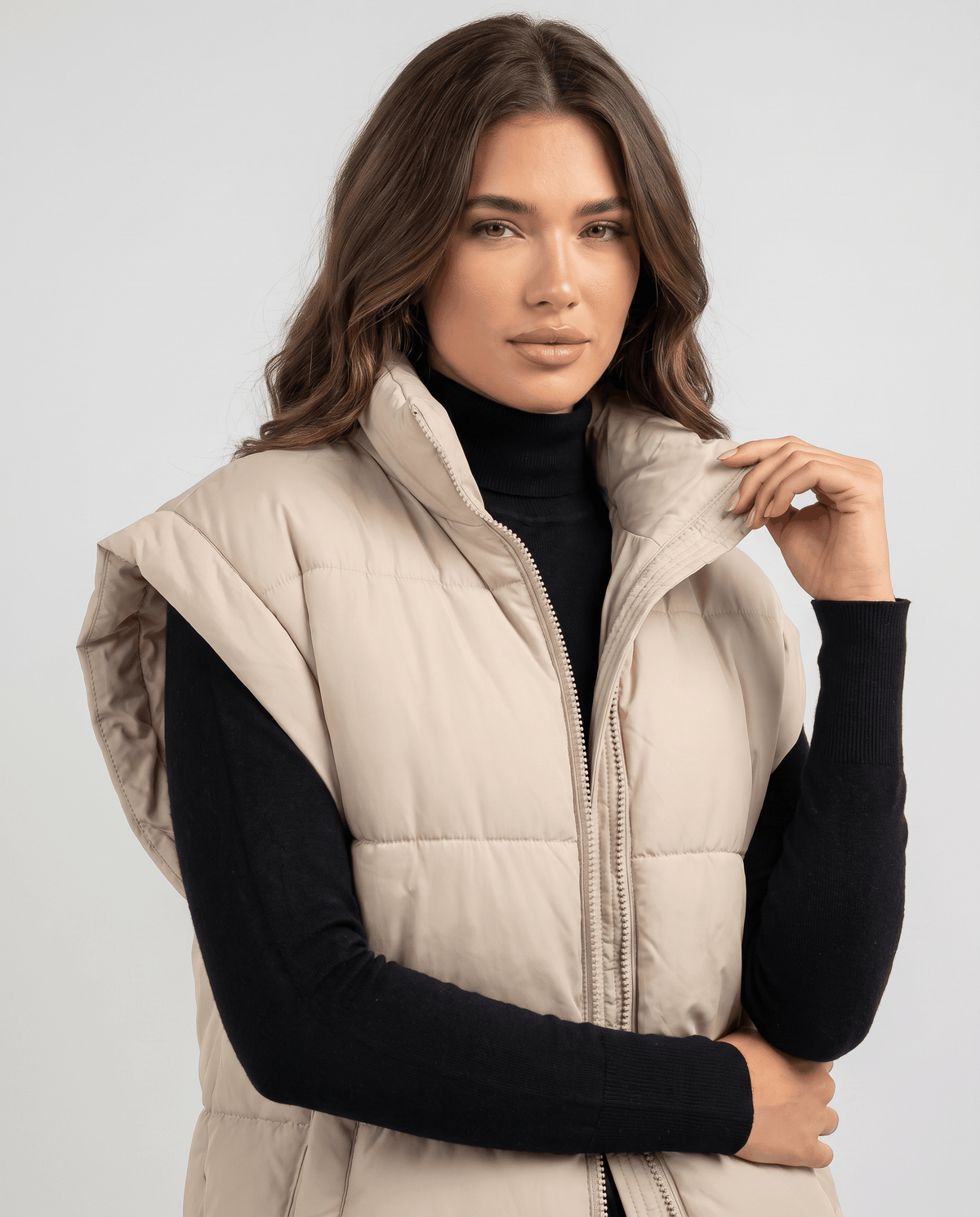 Beige padded vest raised collar and zip shown in close view